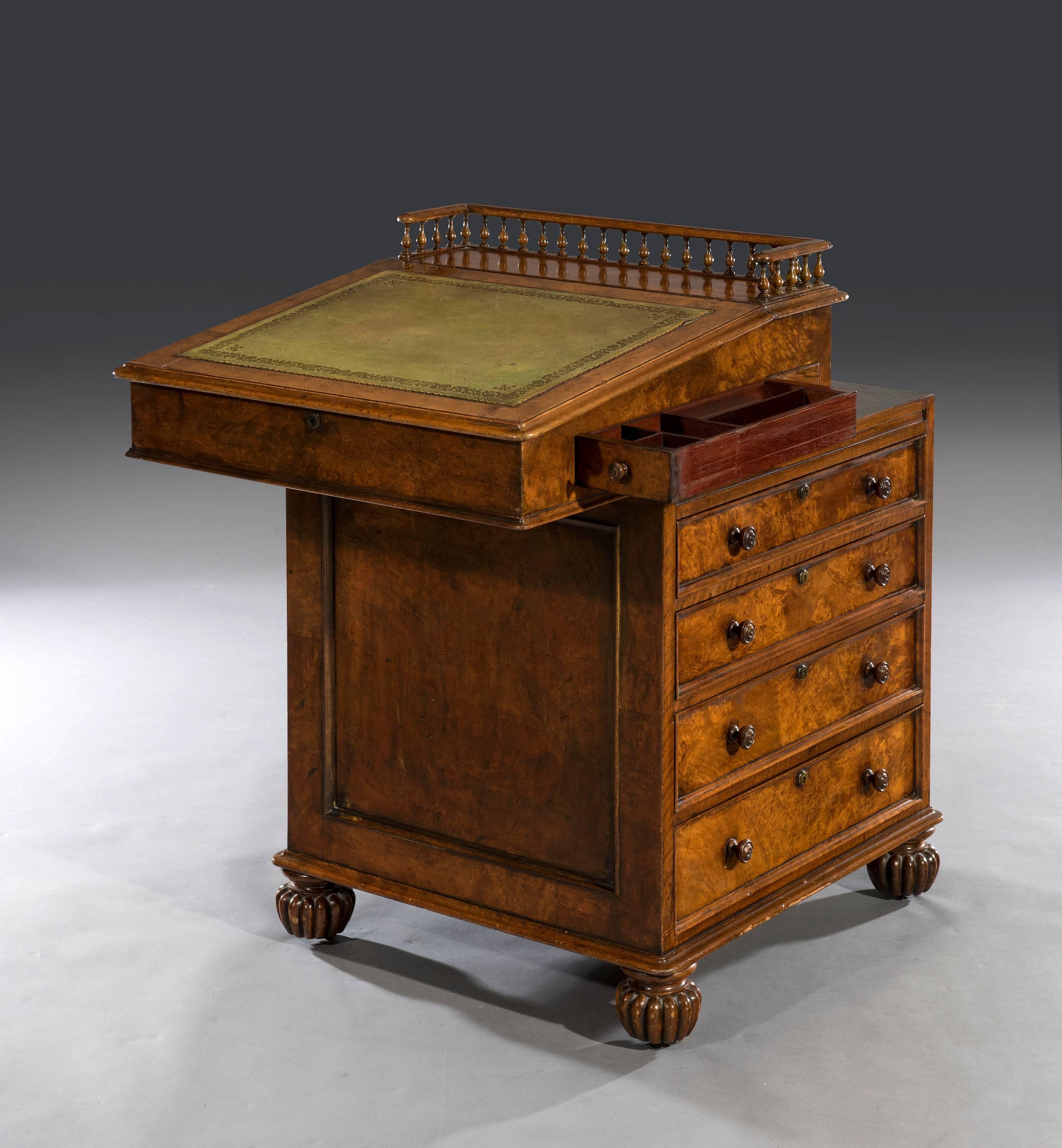 The davenport's walnut gallery is crisply carved with turned baluster-shaped supports above a green leathered writing slope. The rectangular walnut top is veneered with a thumb-nail bevelled edge above a highly figured burr walnut frieze. The frieze