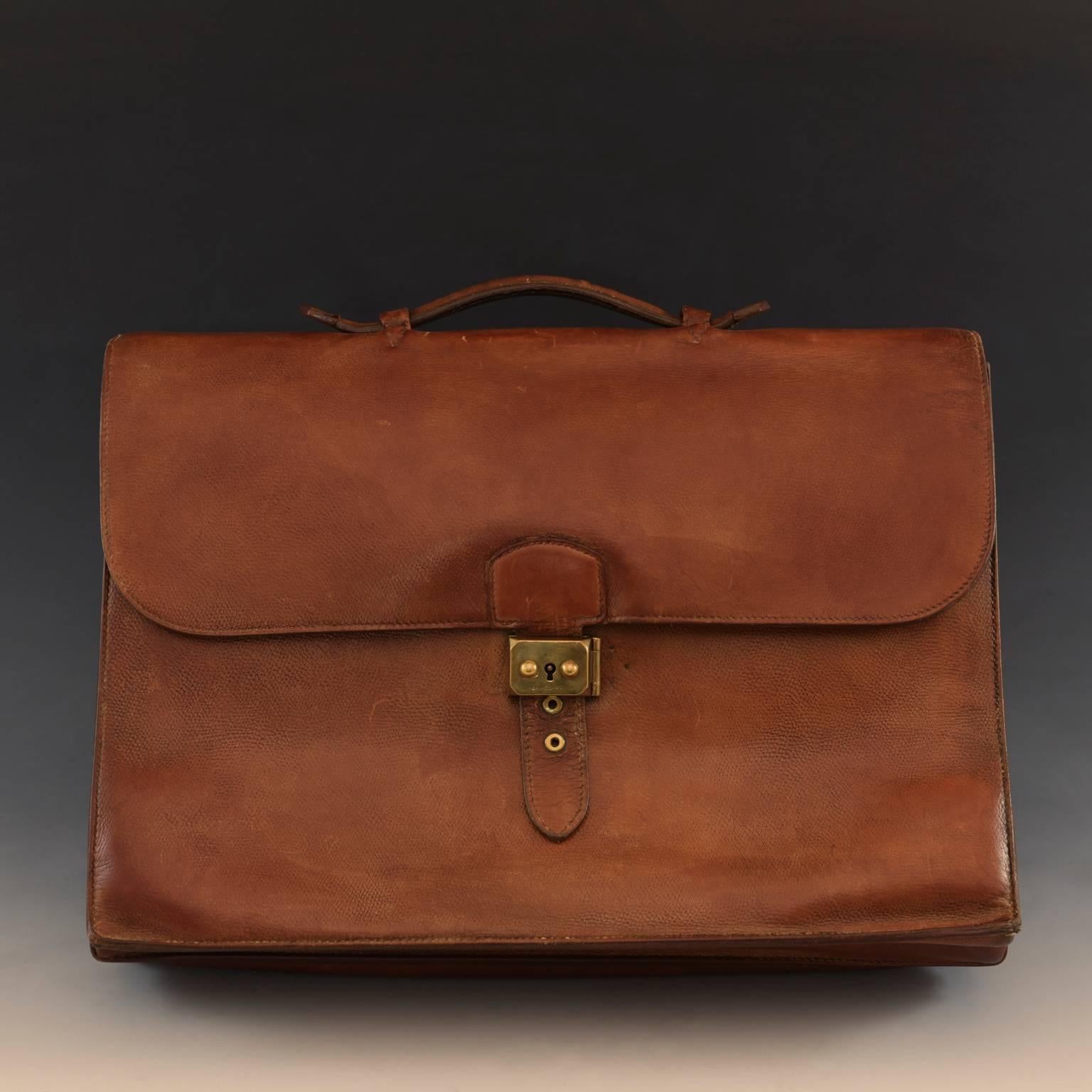 A stylish reddish mid-tan three pocket textured leather 'Sac à Dépêches' briefcase by Hermès. Well-used but well cared for, the case has a polished brass lock that is un-laquered and has a natural glow to it. Unusually, the case, which was made in