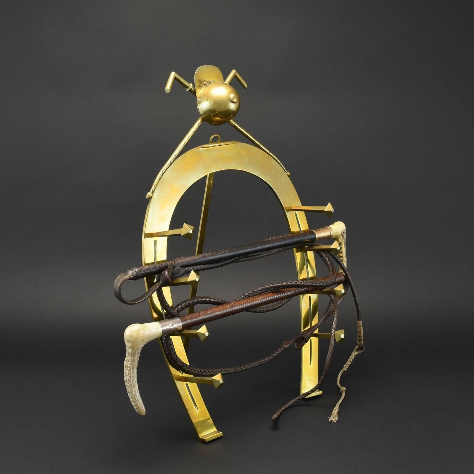 Large-scale Victorian brass whip rack in the shape of a Horseshoe surmounted by a jockey's cap and crossed whips. Has a single central foot stand to the rear but also has a ring so it can be hung on the wall.
This is a rare piece of top quality and