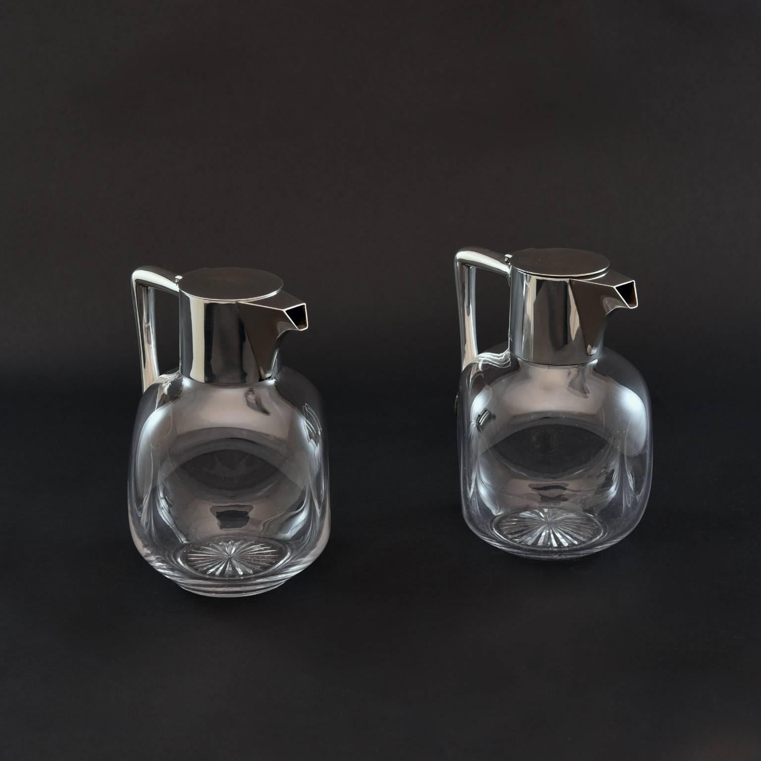 A stylish pair of late 19th century claret jugs by Hukin and Heath. With a handblown spherical glass body that incorporates a dimpled design and a star cut to the base. Silver handle and top hallmarked London, 1896. Deceptive in that although modest