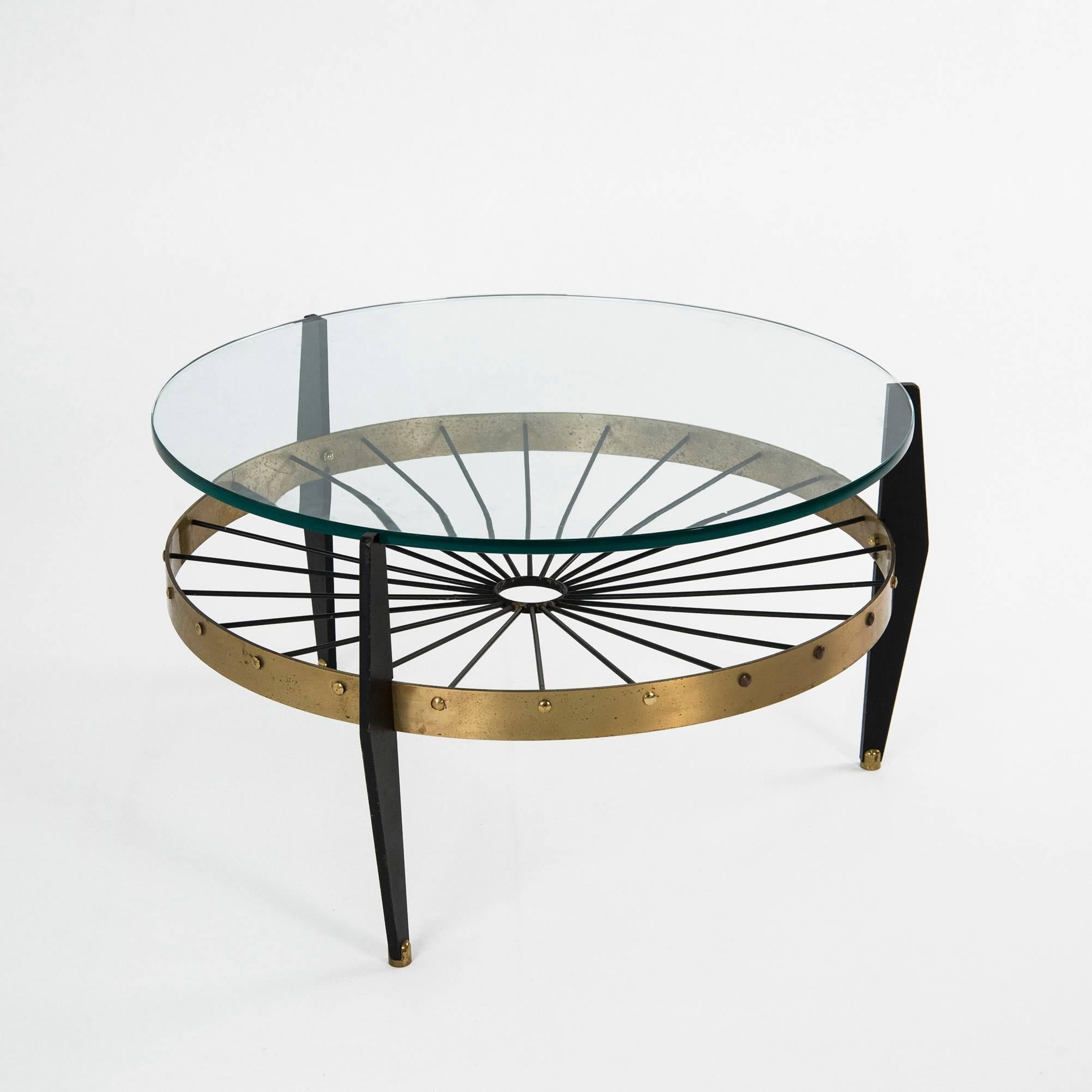 Astonishing low table manufactured in Italy in the 1950s. Black lacquered metal legs, brass circular structure, thick glass top. Good original vintage conditions.