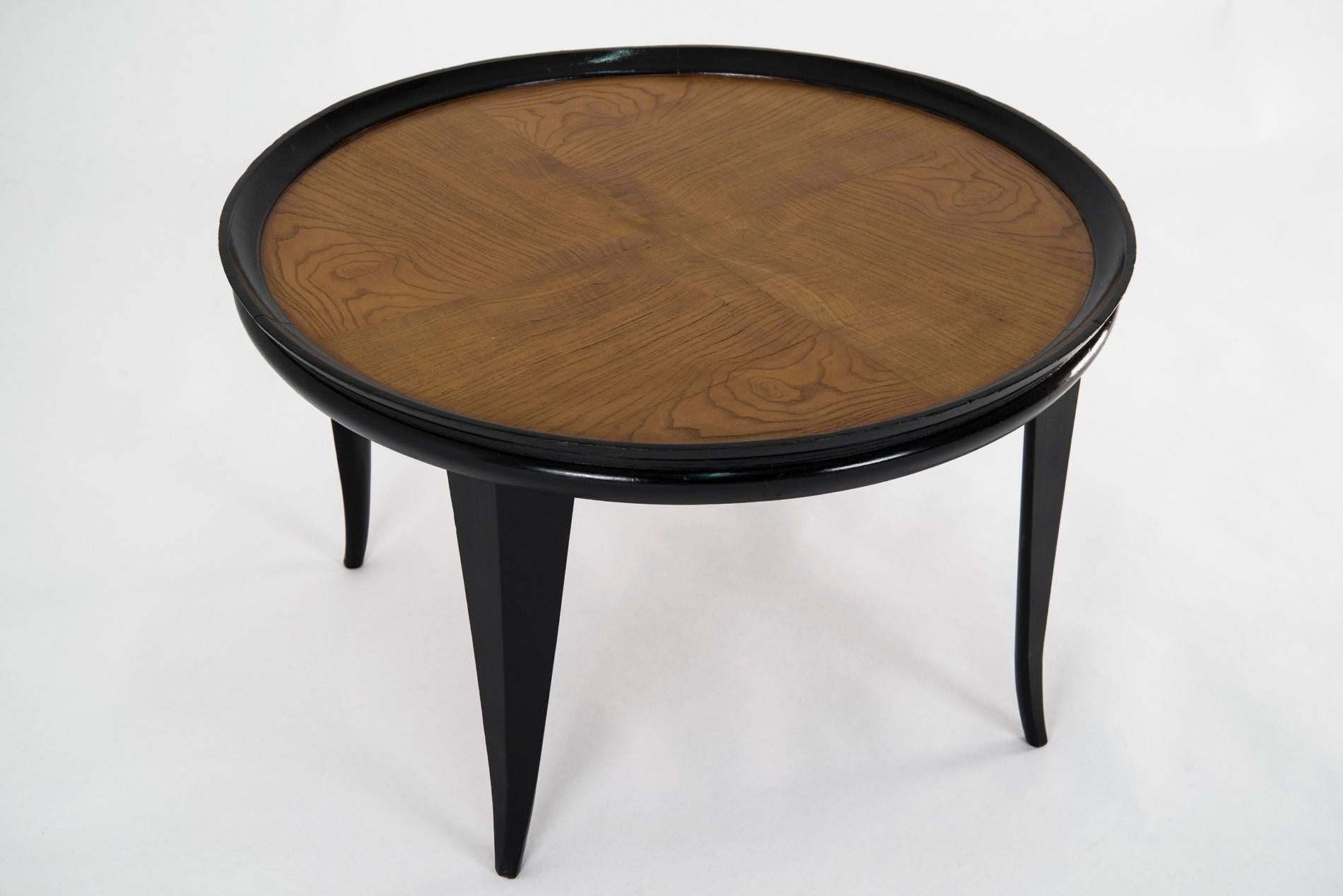 Elegant round coffee table in the manner of Gio Ponti, manufactured in Italy in the 1940s. Carved black lacquered wooden base, top in a natural veneer. Good original vintage conditions.