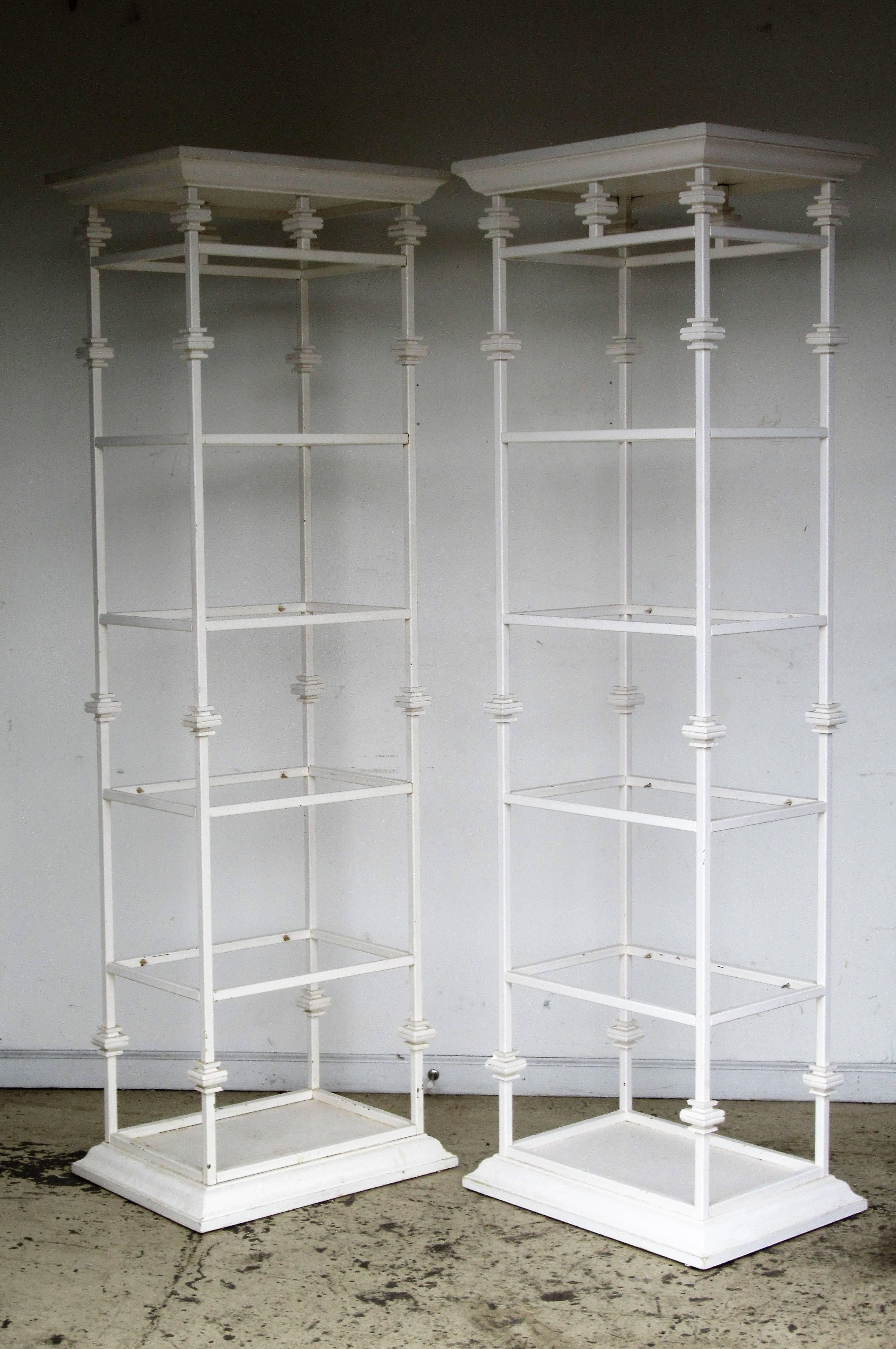 Great looking pair of iron and composite Hollywood Regency classical architectural form etageres in older white painted surface. Each with four smoked glass shelves. See all pictures.
 