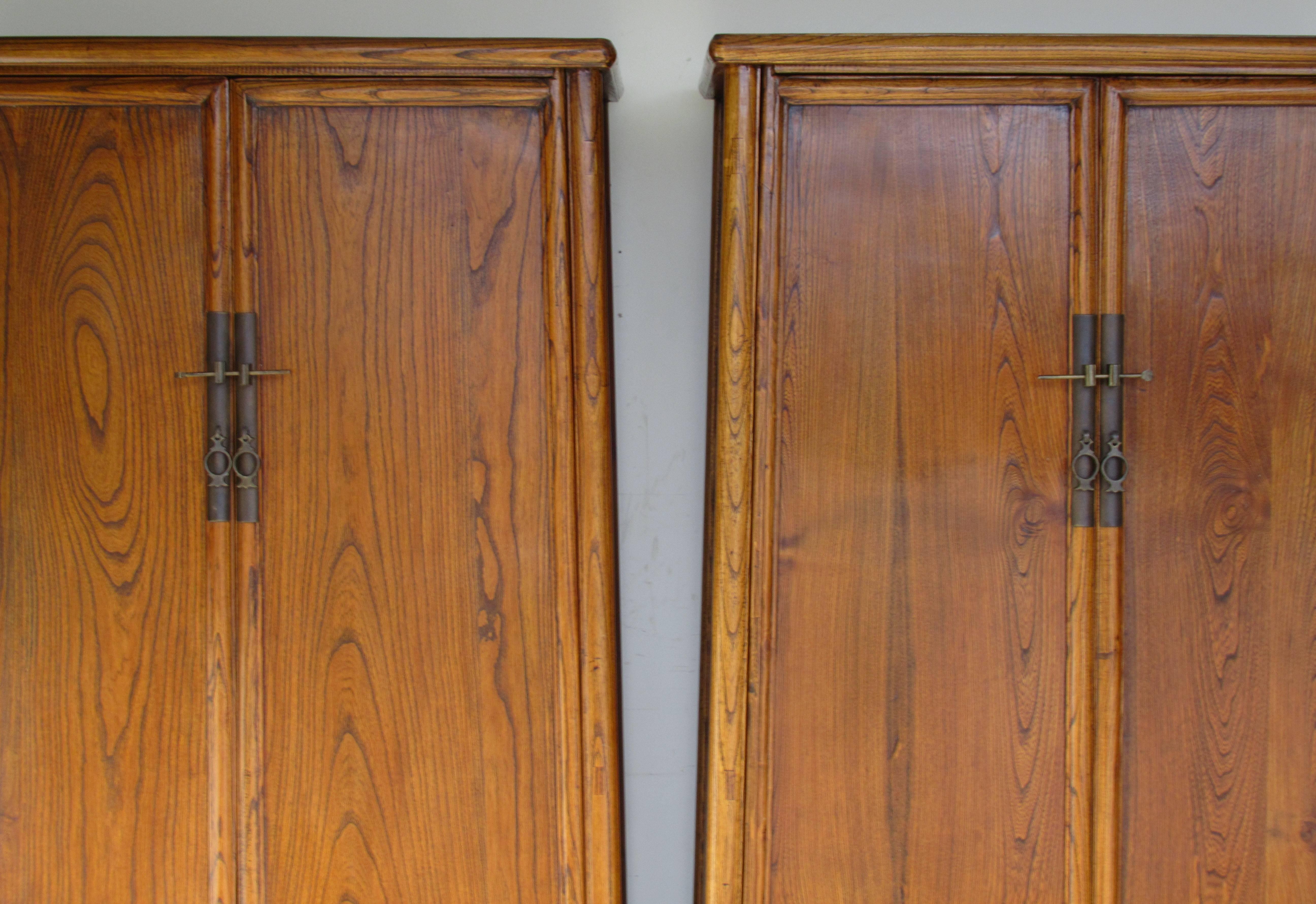 A pair of antique 19th century Chinese hardwood elm cabinets with two doors / two drawers / fine bronzed brass hardware / rounded corners / shelved interior / mortised construction and a sloping tapered form. Exceptional quality with beautiful