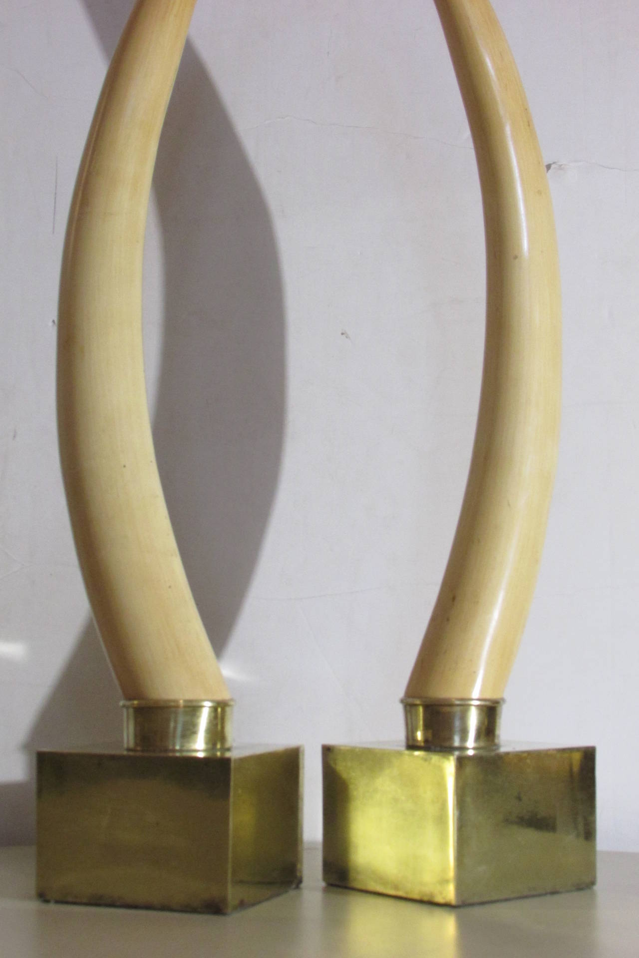 A good looking pair of Hollywood Regency faux ivory tusk sculptures mounted on the original square brass pedestal bases, circa 1960-1970.