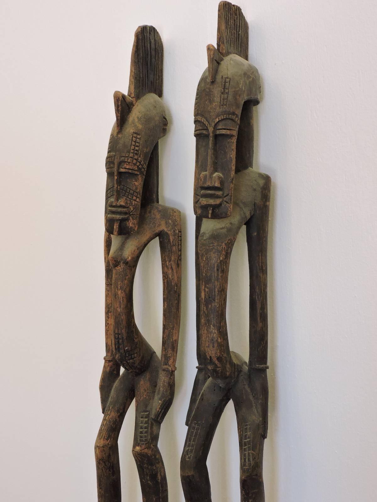 A tall pair of carved wood female and male Ivory Coast Senufo rhythm pounders in nicely aged worn surface - circa 1960's - 1970's