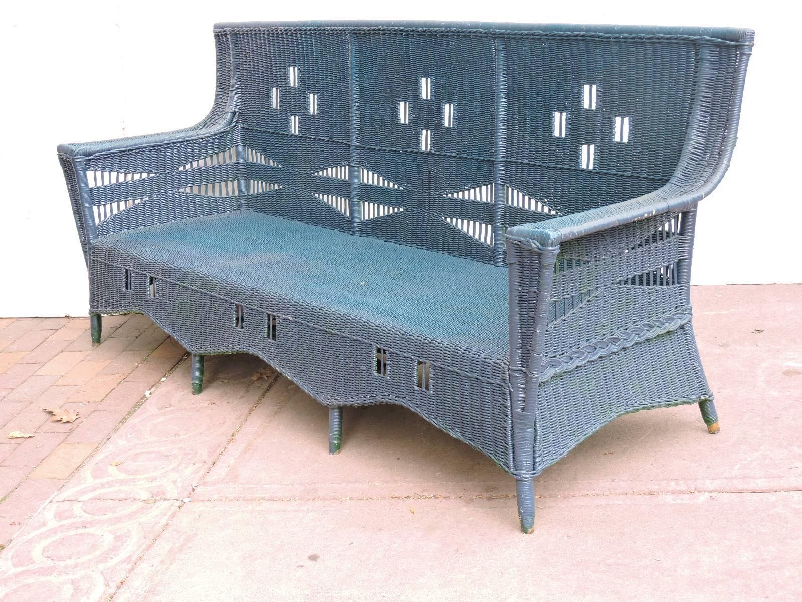Antique high back wicker sofa in older dark teal blue painted surface with a beautifully elongated form and a repeating square cut-out design on back rest and front skirt. Very substantial, heavyweight and solid as a rock with no breaks. In the