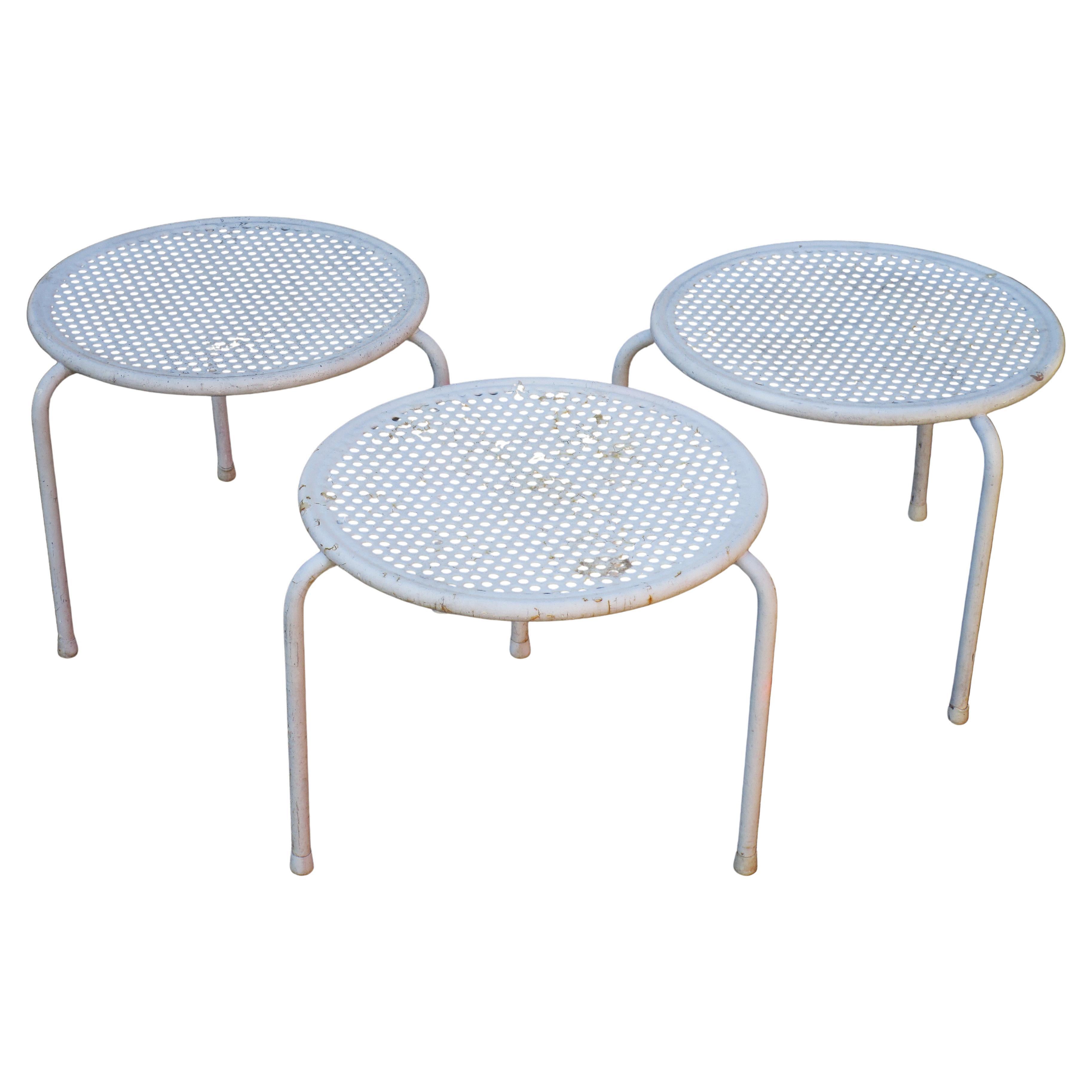 Matching set of three mid 20th century modern all original white enamel painted metal perforated circular top stacking tables with tri leg base - made in Italy by Emu, circa 1960's. For garden, patio, interior.  Measure 14