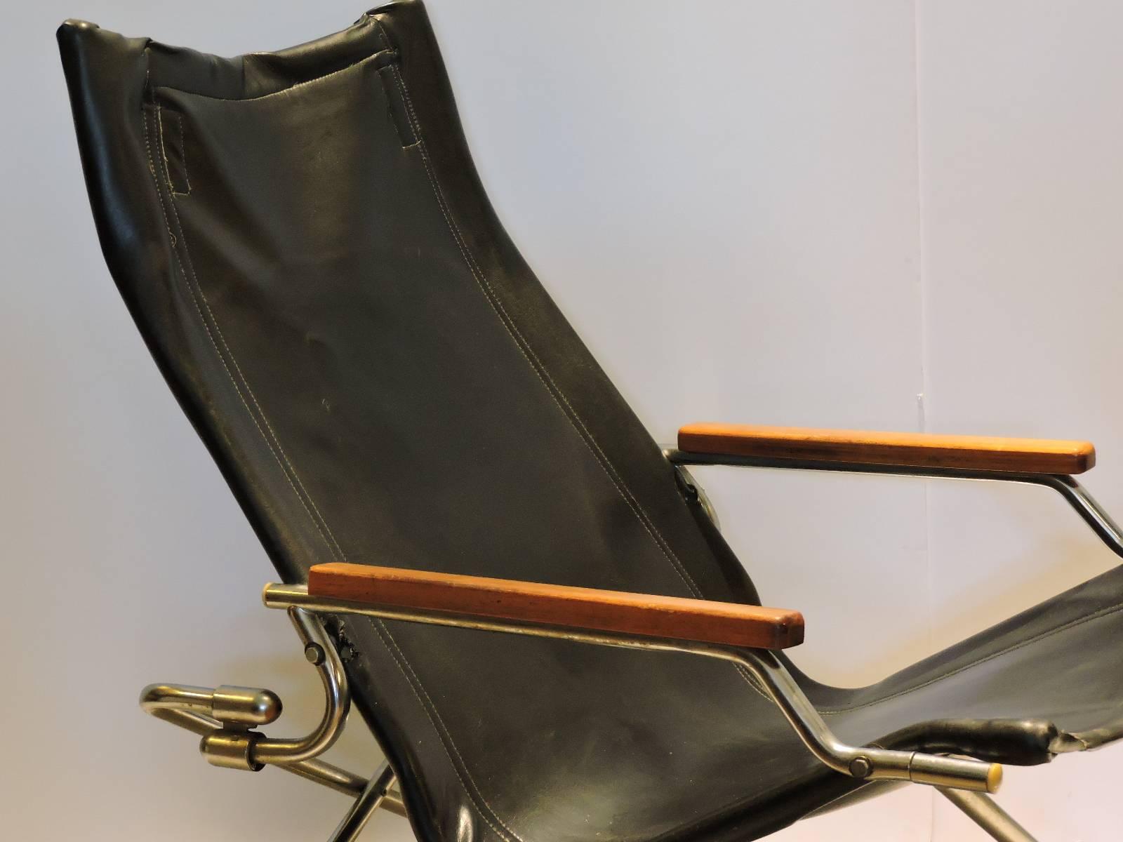 Folding 1970s modernist sling chair having a chrome-plated steel framework with wood arm rests and the original black faux leather vinyl upholstery. Manufactured by Uchida, Japan. Similar in design to the Takeshi NII NY folding chair also by Uchida.