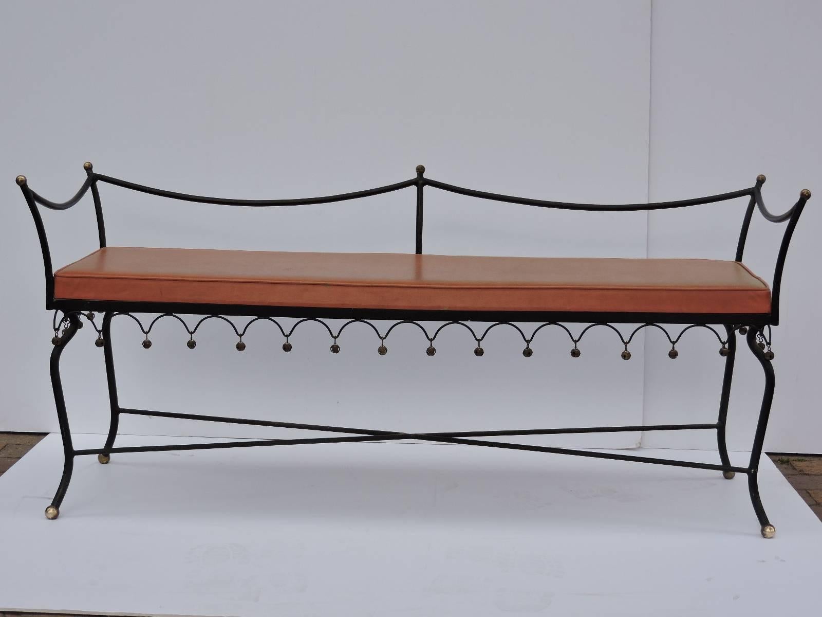 A black iron bench mounted with hanging brass bells at front, sides and back of curvilinear skirt and brass ball finials at three top posts of peaked back and front top sides. Very good all original vintage condition with nicely aged surface patina