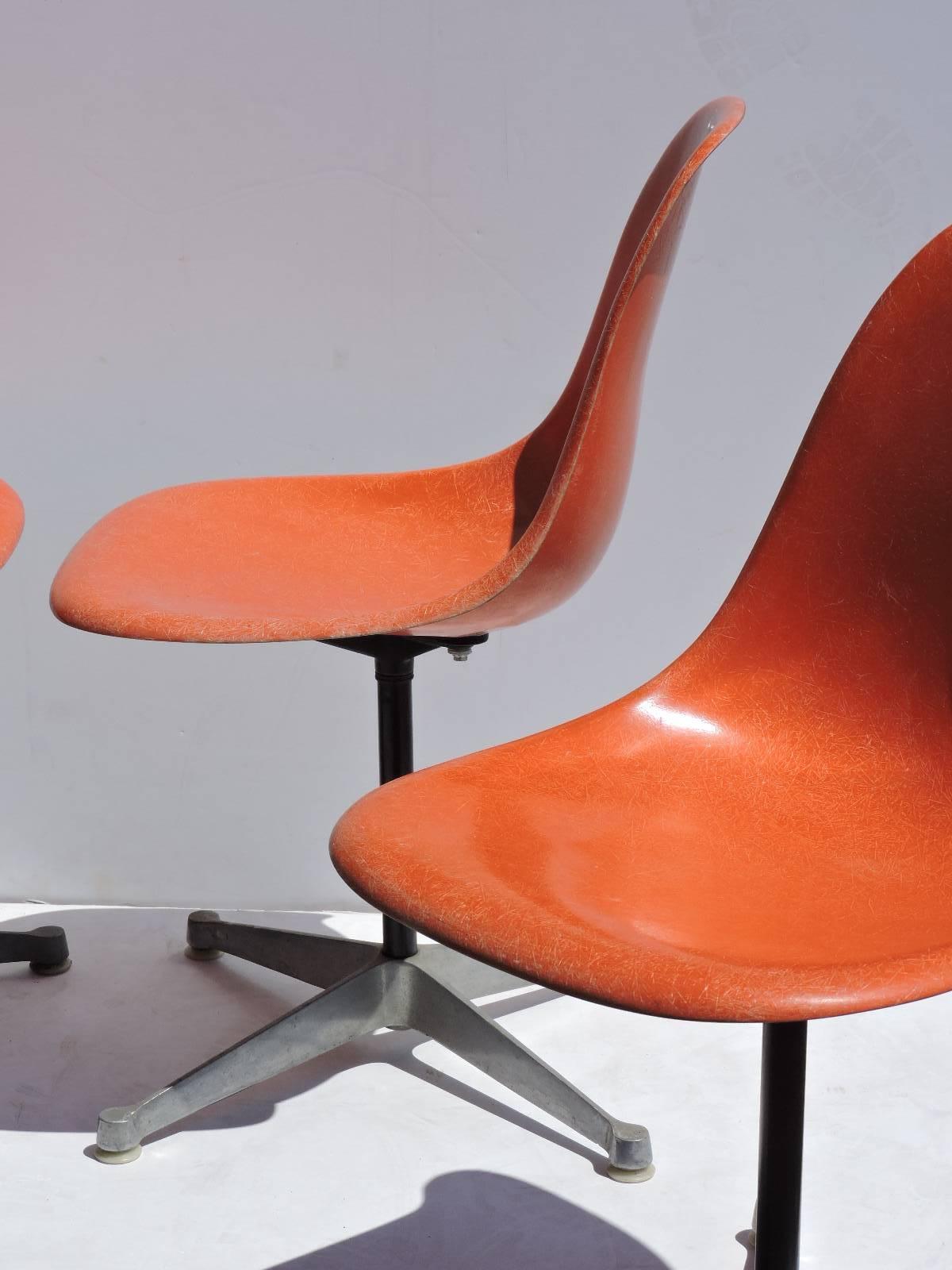 A set of four Charles and Ray Eames for Herman Miller matching deep orange fiberglass swivel chairs with four-star aluminum bases and original nylon foot pads. See all pictures.