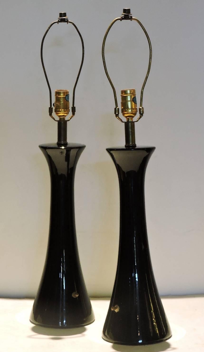 Pair of mid-20th century modernist hourglass form high gloss black glazed ceramic lamps with a clean simple design that would be compatible for many interior styles.