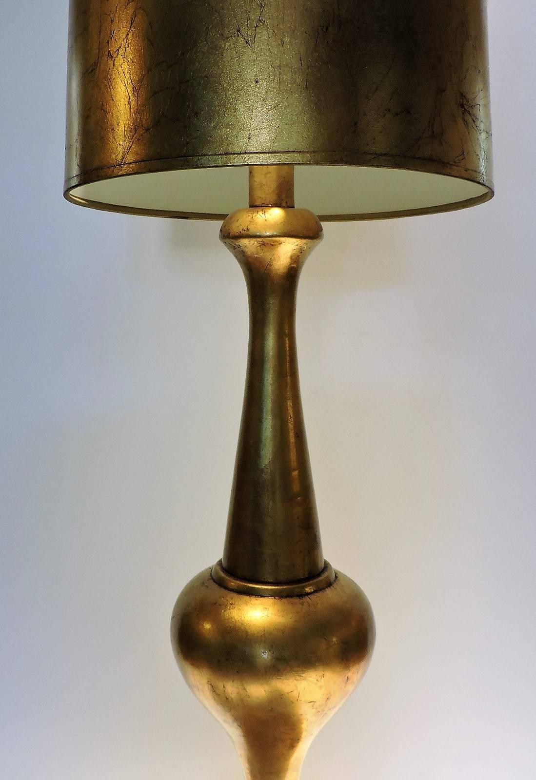 Hollywood Regency brilliantly gilded table lamp with beautifully proportioned sleek statuesque form. Retains great original tall tapered textured marbleized gilt shade. Great quality. In the style of The Marbro Lamp Company, circa 1960s.