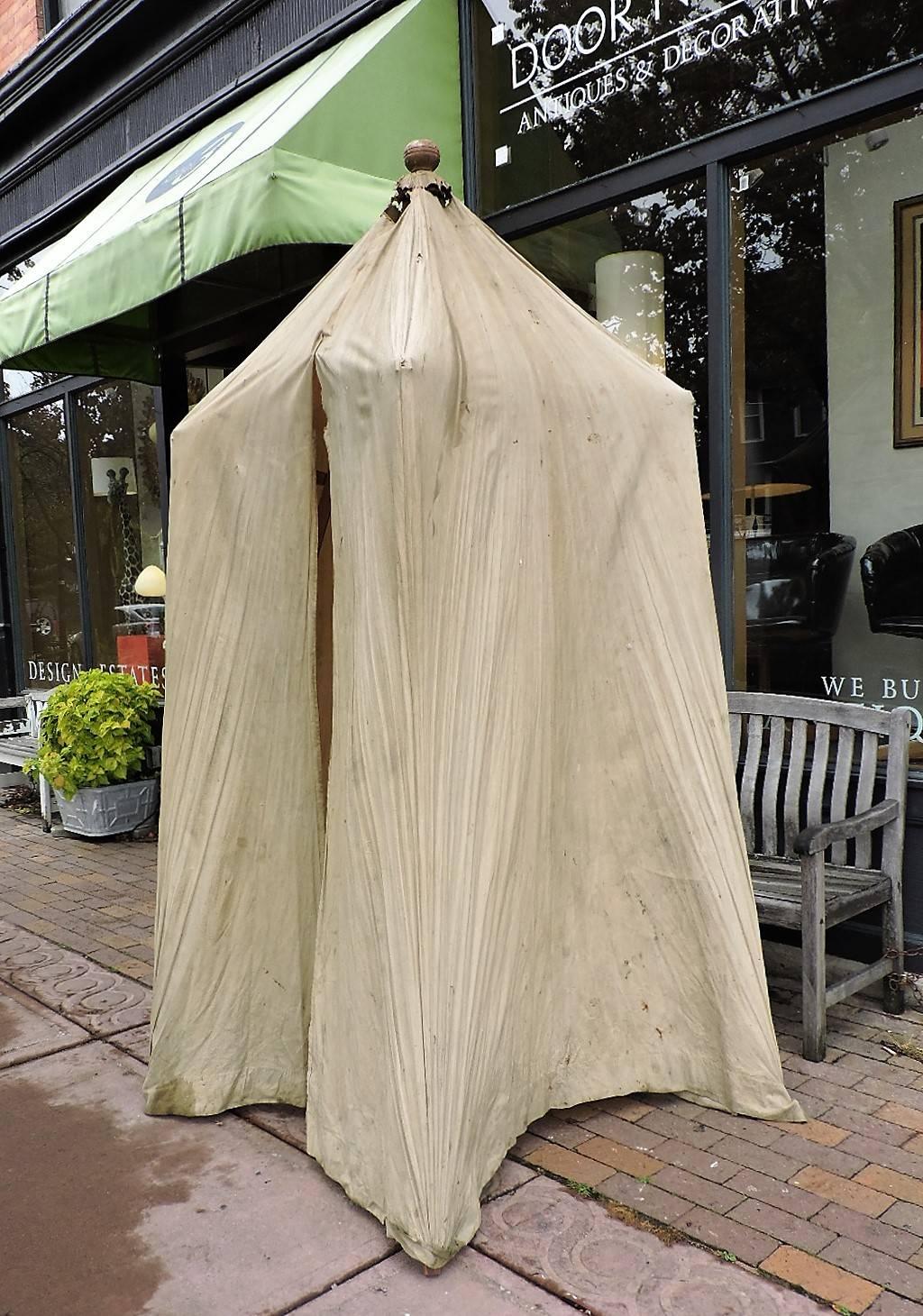 Antique folding pagoda form portable cabana. Natural cotton linen fabric exterior with collapsible wood interior frame work with metal tabs and large pegged and turned wood round finial at peaked top. Overall intact vintage condition with some wear