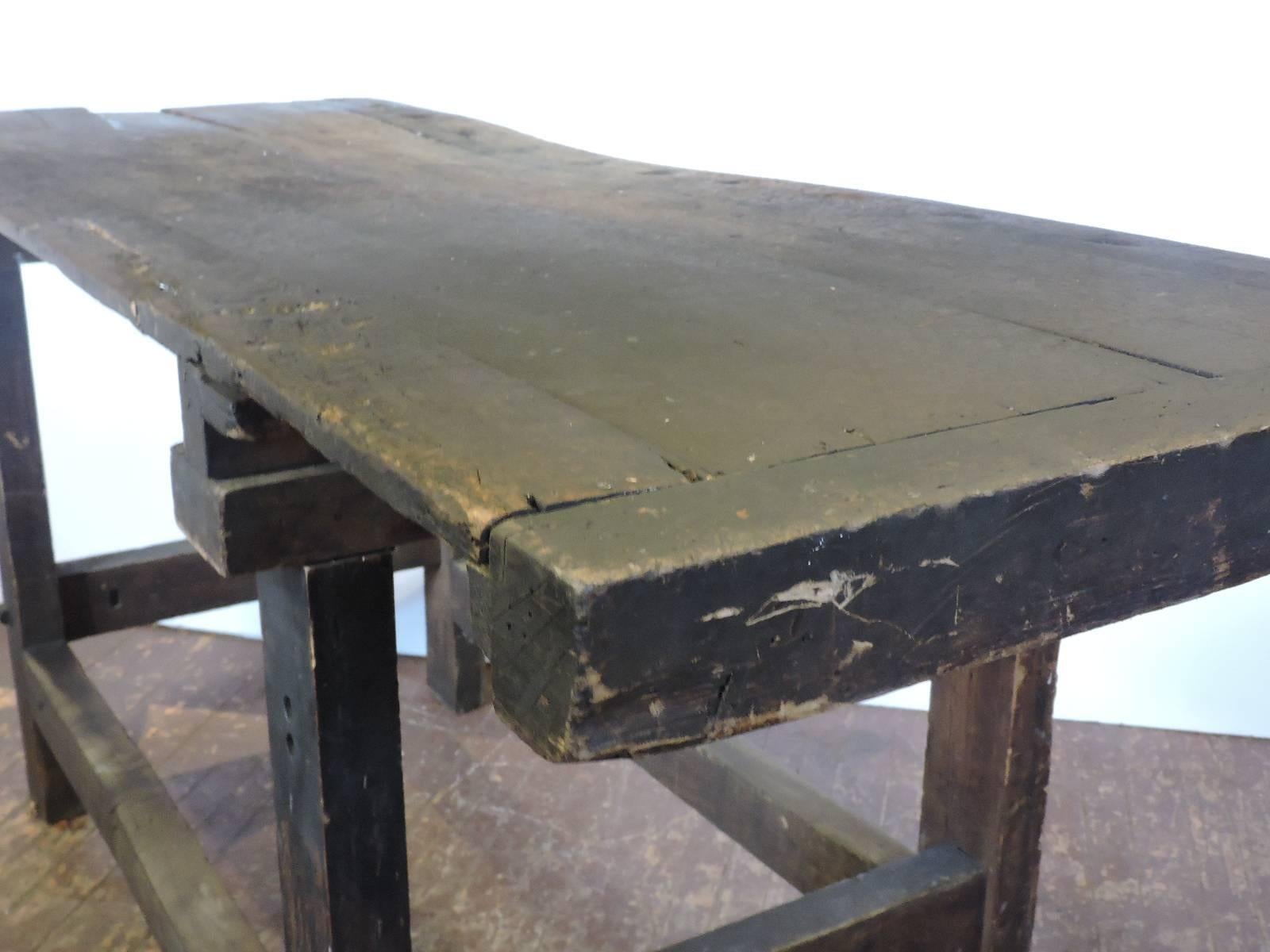 Antique American carpenters work table / woodworkers bench in very aged worn distressed old surface to heavy thick planked and bolted wood board top raised on square wood and iron bolted legs joined by hand planed stretchers on all four sides.