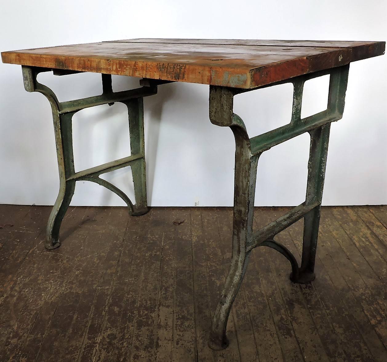 Antique American Industrial factory work table bench with original architectural cast iron base and large round inset round bolt riveted two inch thick three board wood block top. As found old surface to wood top and beautifully aged worn green