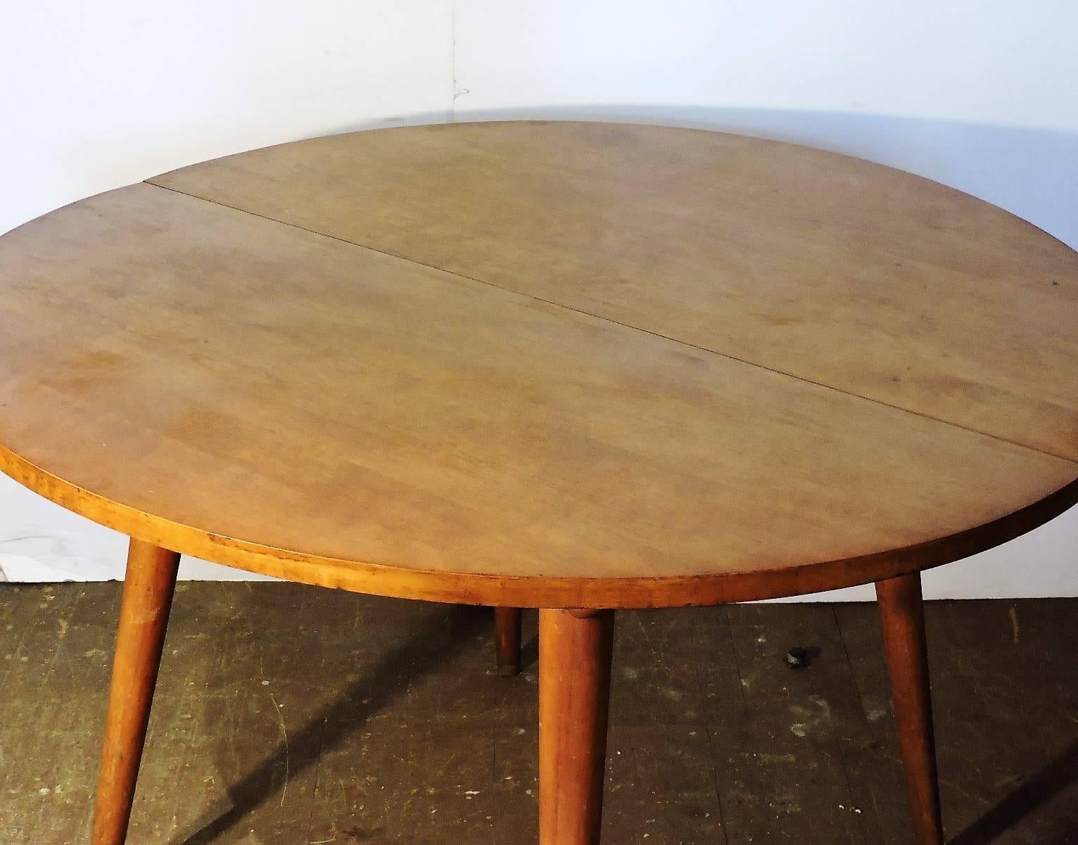 A Russel Wright extension dining table for Conant Ball American Modern line with round top and perfectly tapered legs inset with long angled rods at top. Beautiful sculptural form, circa 1940-1950. Table shown in primary picture without the two