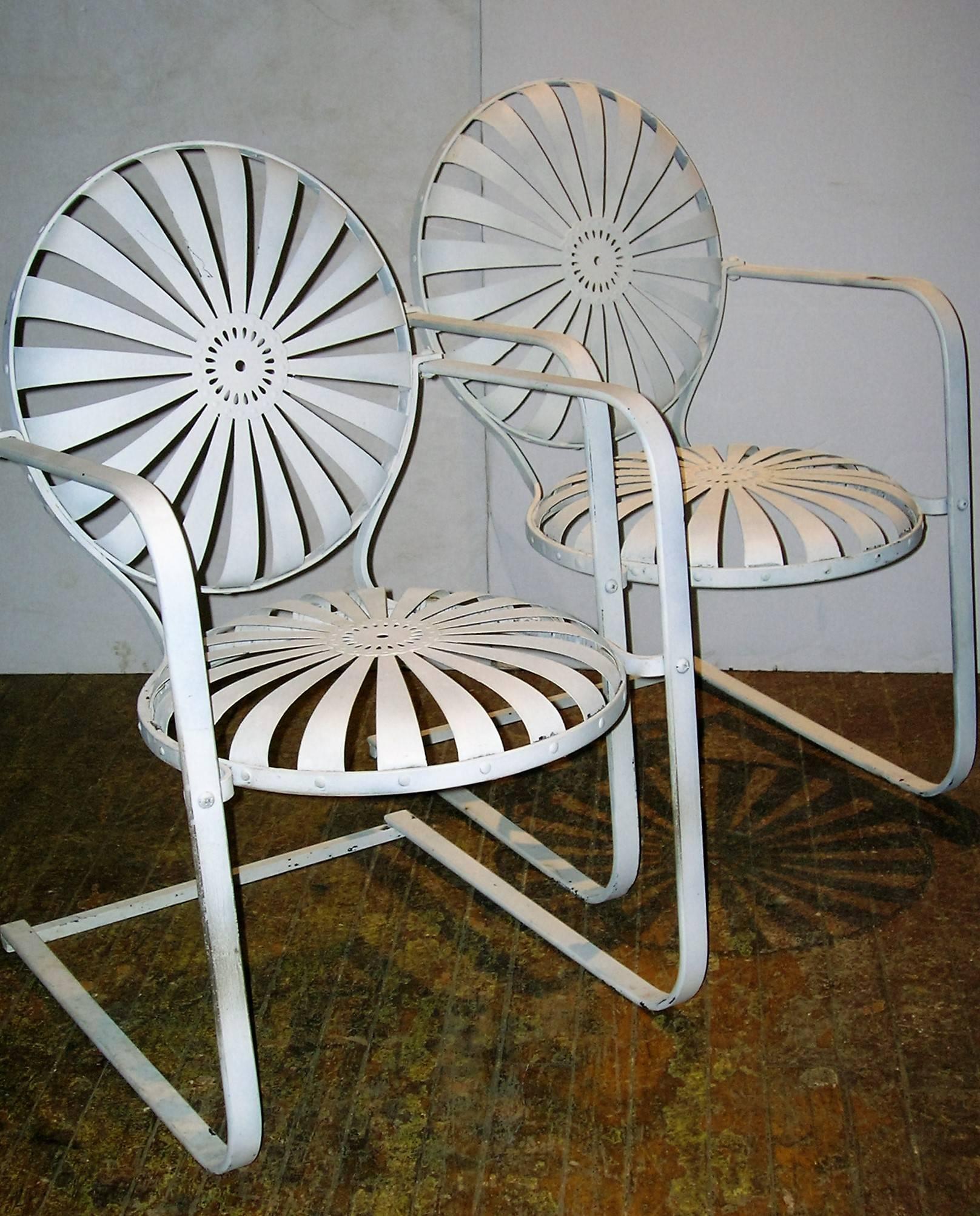 Pair of iron garden chairs with rocking cantilever base and pinwheel sunburst pattern spring seats and backs designed by Francois Carre, circa 1930s.