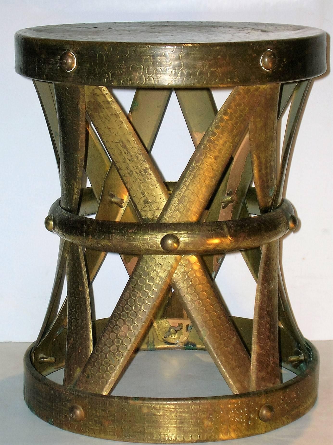 1970s Hollywood Regency riveted brass X-form drum stool taboret table with beautifully aged color patina and nicely detailed metal work. See all pictures.