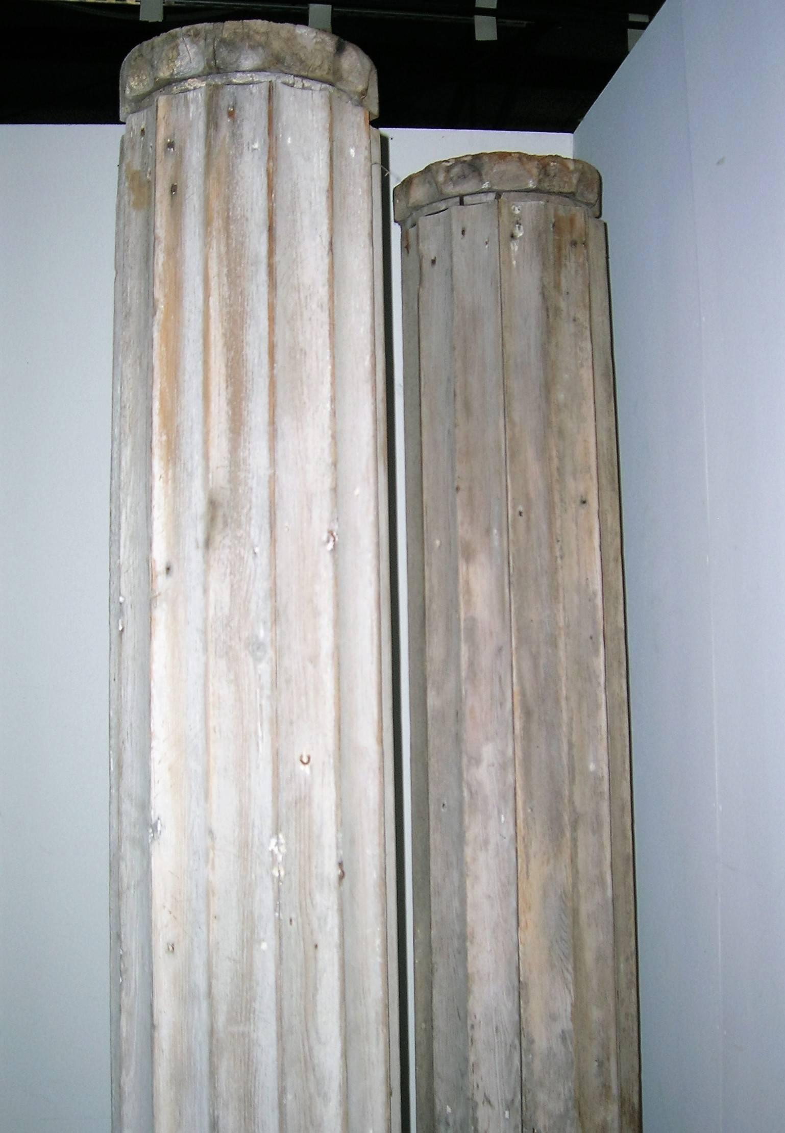 Antique Greek Revival fluted architectural columns with Doric capitals in all-over beautifully aged very pale driftwood gray weathered surface. Measures: Stand 88 inches tall x 12 inches wide with a 36 inch circumference at widest point bottom.