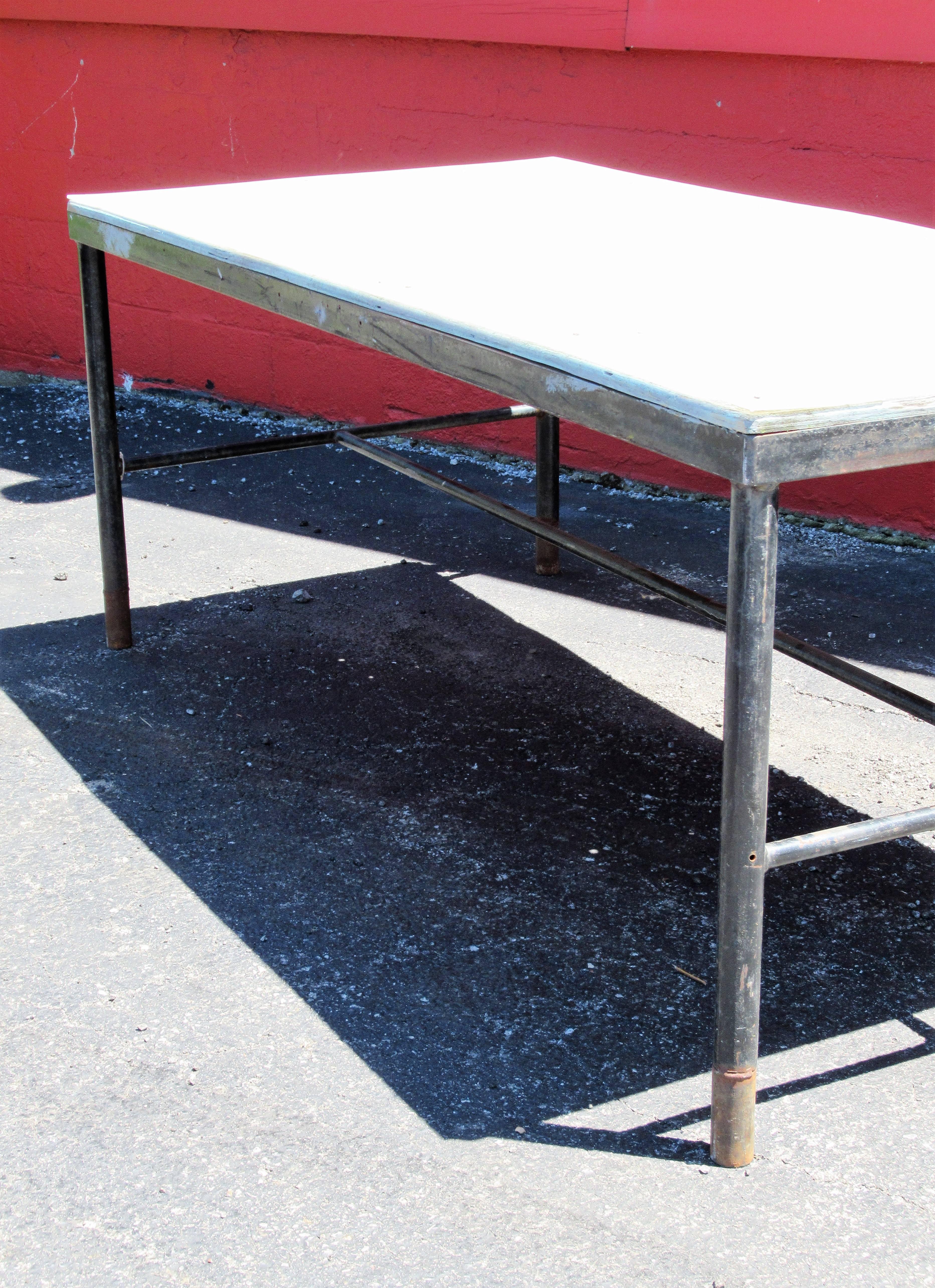 Large antique American Industrial factory work table, the tubular iron base legs with two side stretchers joined by long centre stretcher. The original plywood top covered with screwed down acrylic plexiglass sheet. Beautiful architectural form.