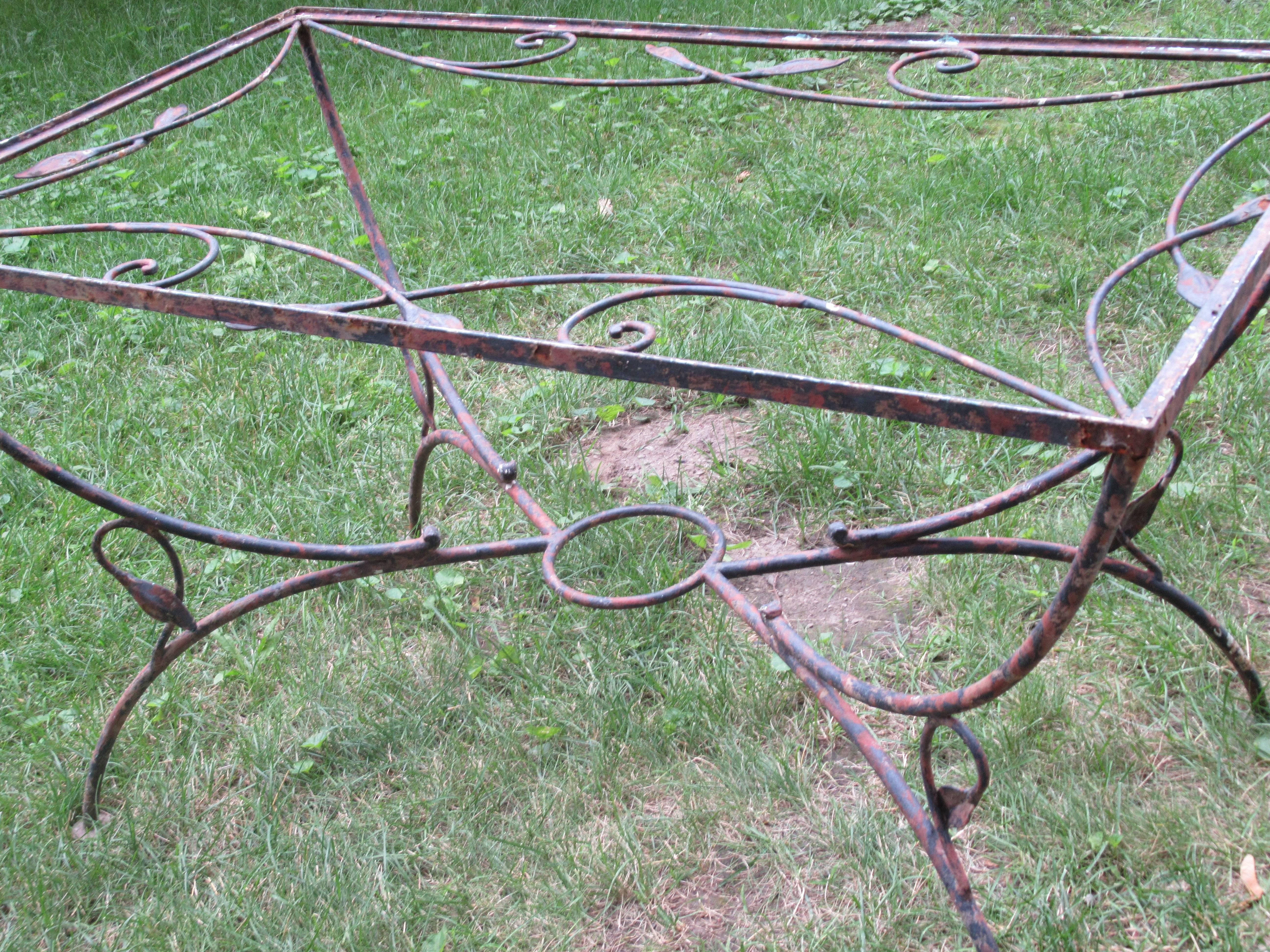 A wrought iron garden patio dining table with beautifully aged old worn paint layered surface. Finely detailed metalwork and very good quality. Style of or attributed to Salterini, circa 1950-1960.