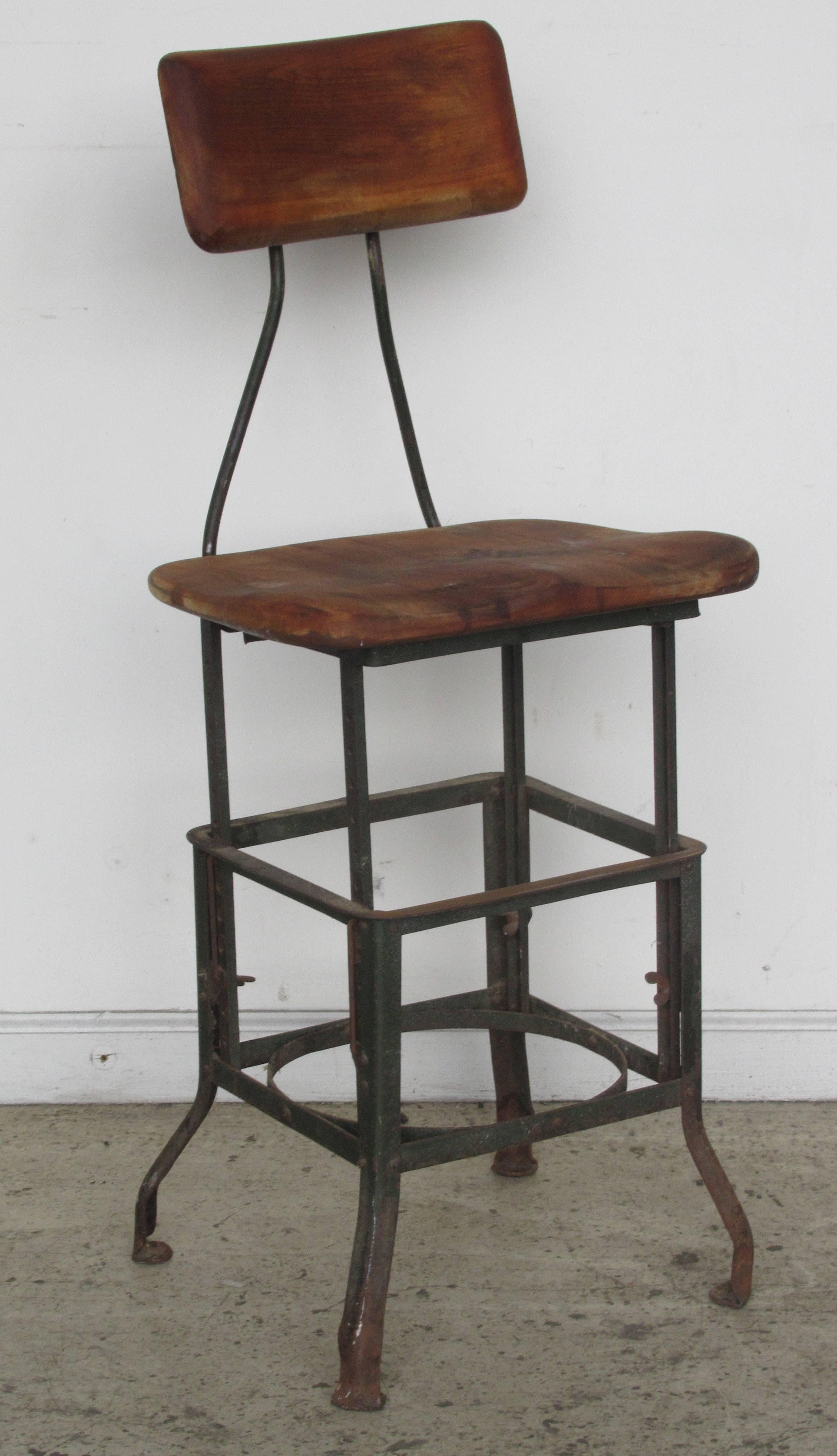 Early antique industrial task chair stool with adjustable height iron framework and solid contoured wood   seat and backrest. American - circa 1920 - 1930