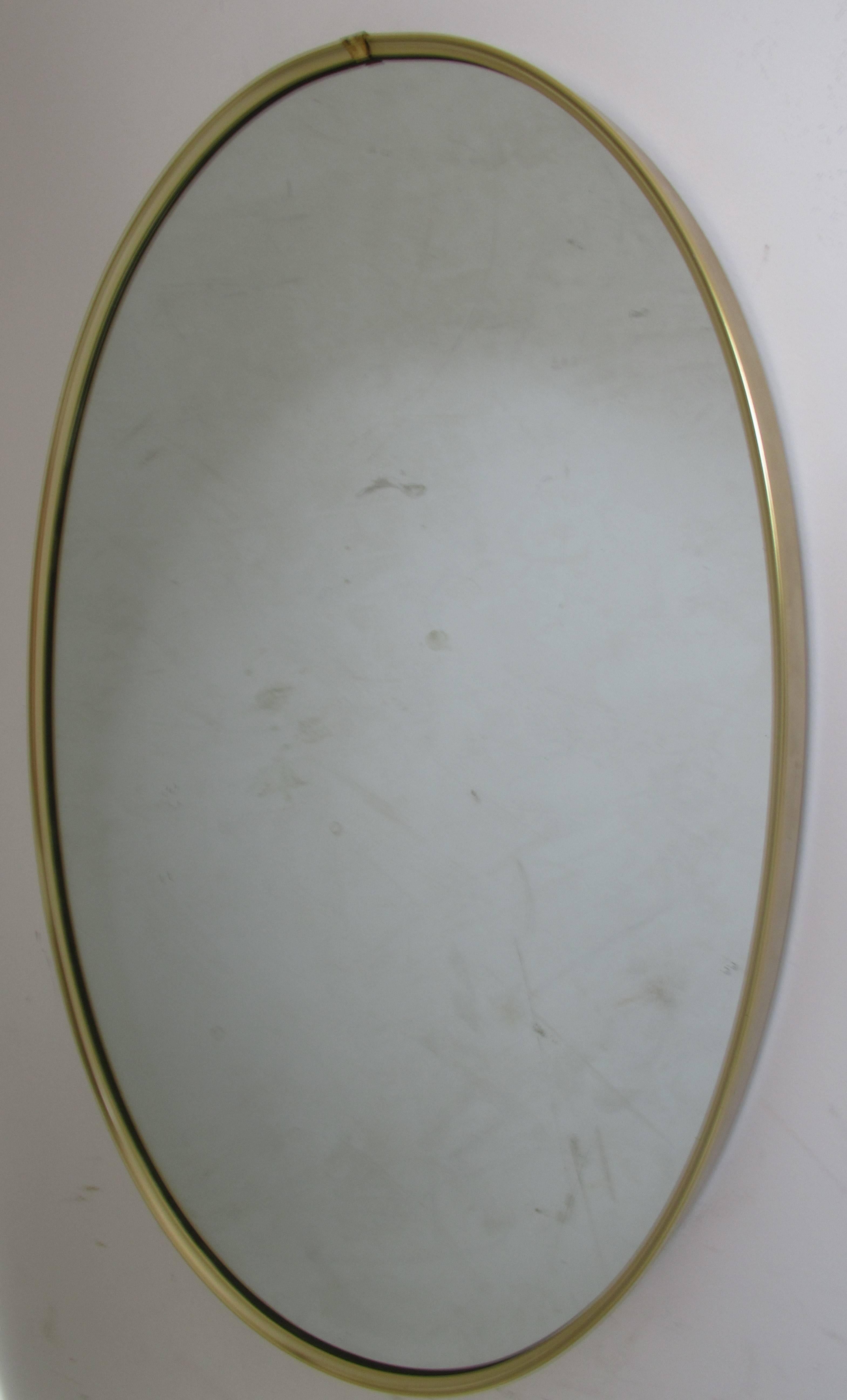 Oval brass wall mirror in the style of Gio Ponti, circa 1960.