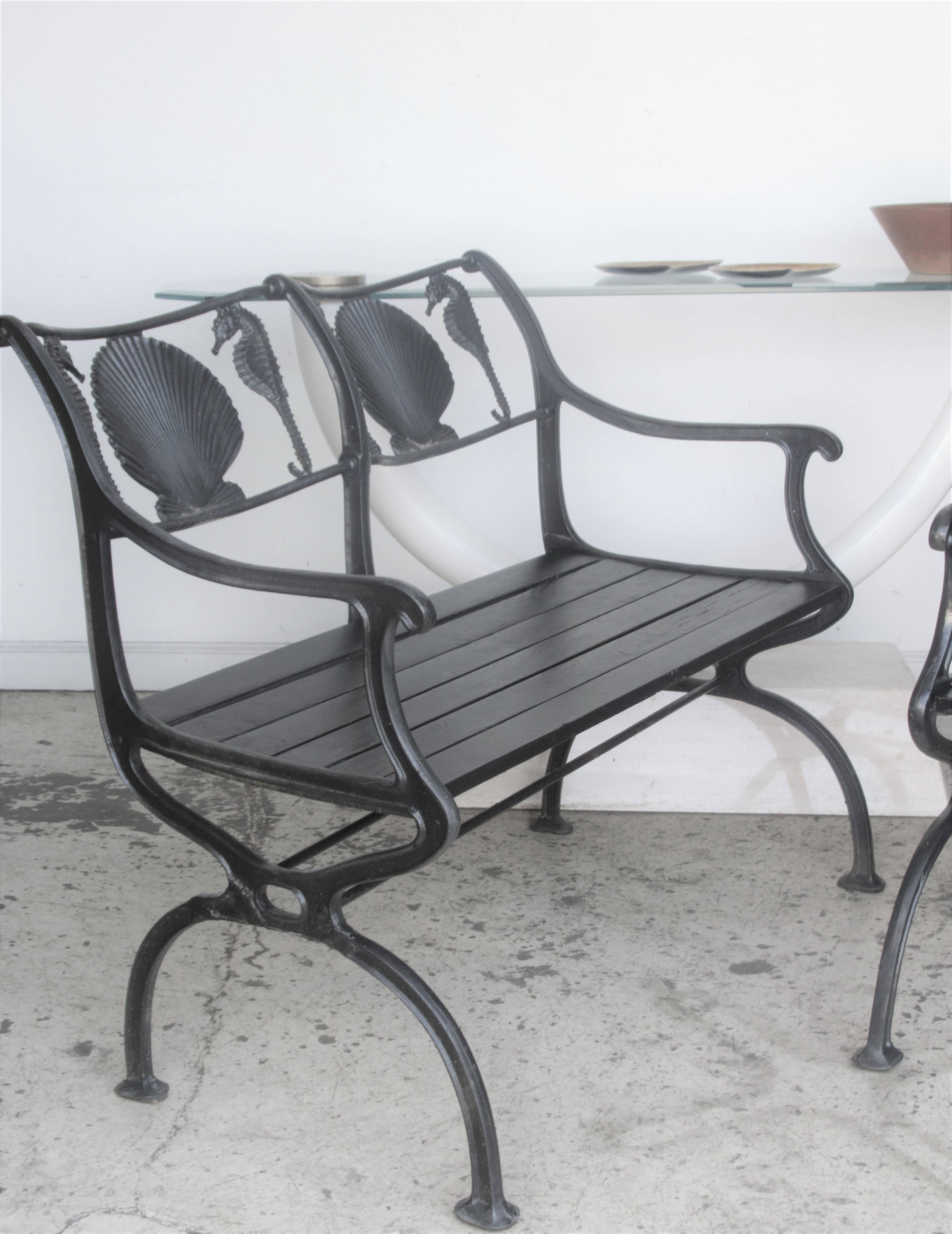 A very hard to find four-piece antique American cast iron set of garden furniture consisting of two matching benches and two matching armchairs with a finely detailed design of raised scallop seashell and seahorses on the backs of all pieces. Signed