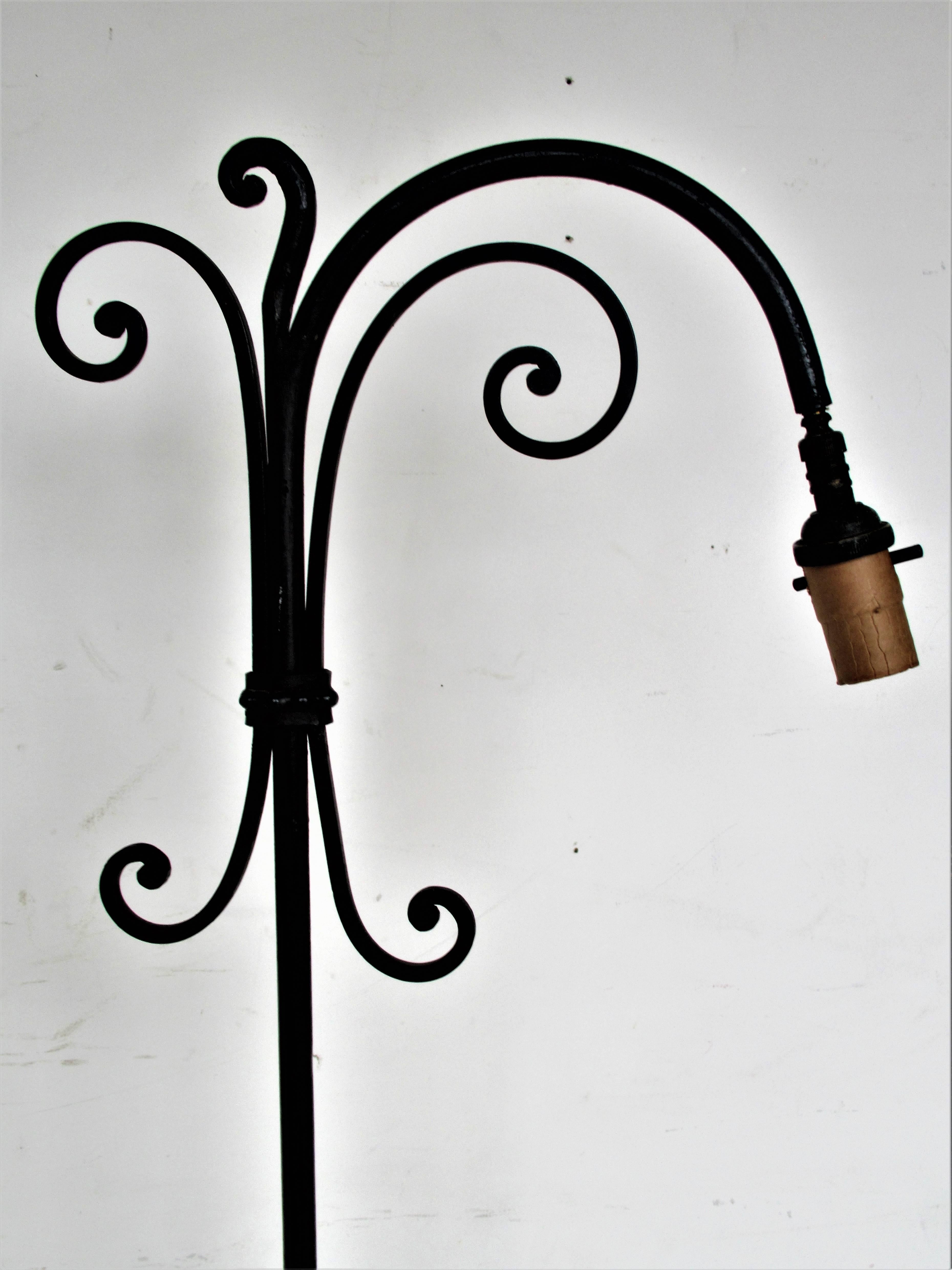 Wrought iron adjustable height floor lamp in a transitional Art Nouveau / Arts and Crafts design. Finely hand-wrought in original nicely aged blackened surface with light wear oxidation to metal. Highest height is 57 inches / lowest height is 43
