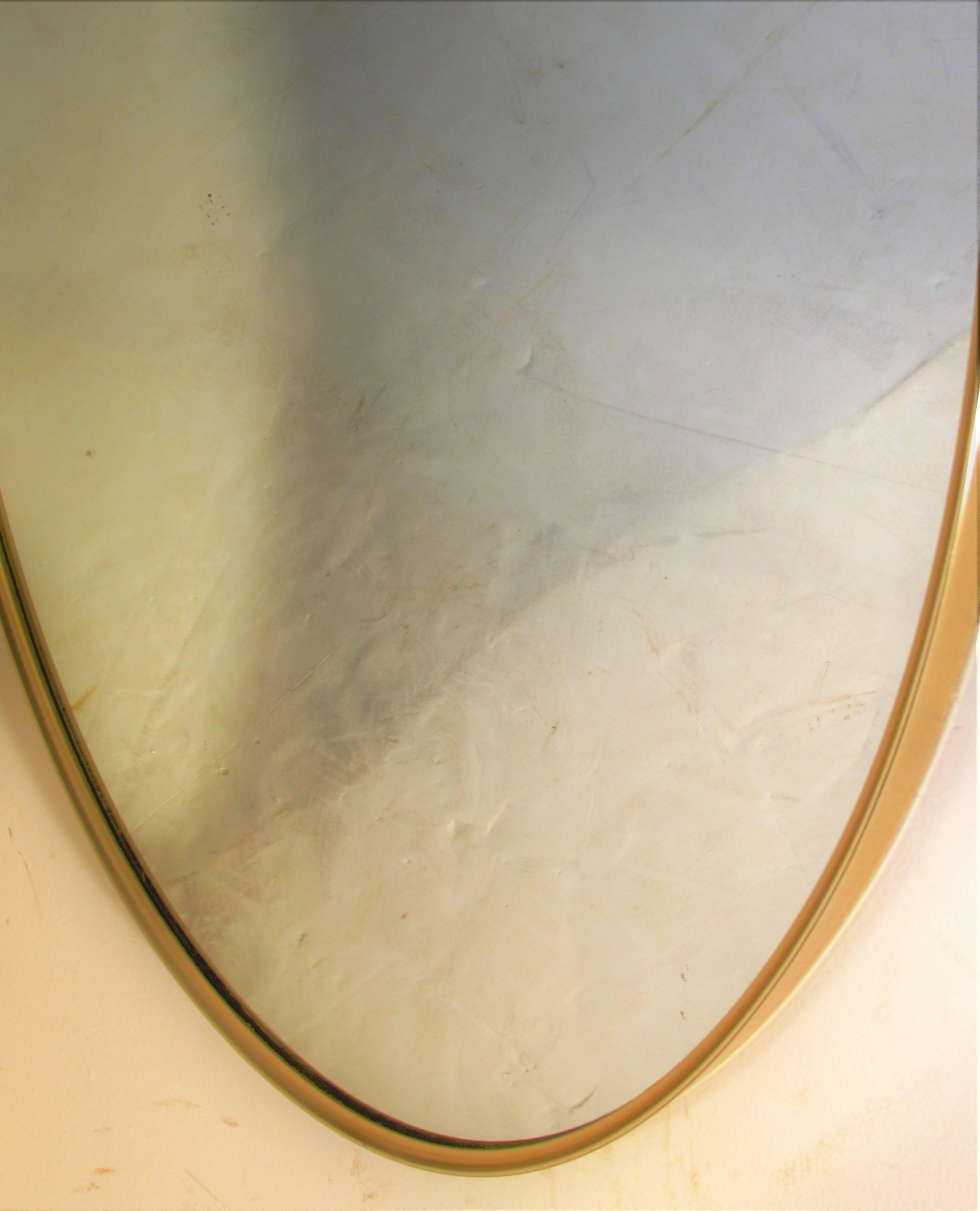 Oval brass framed mirror mounted with original ring finial at top in the 1960s Italian modernist style of Gio Ponti.