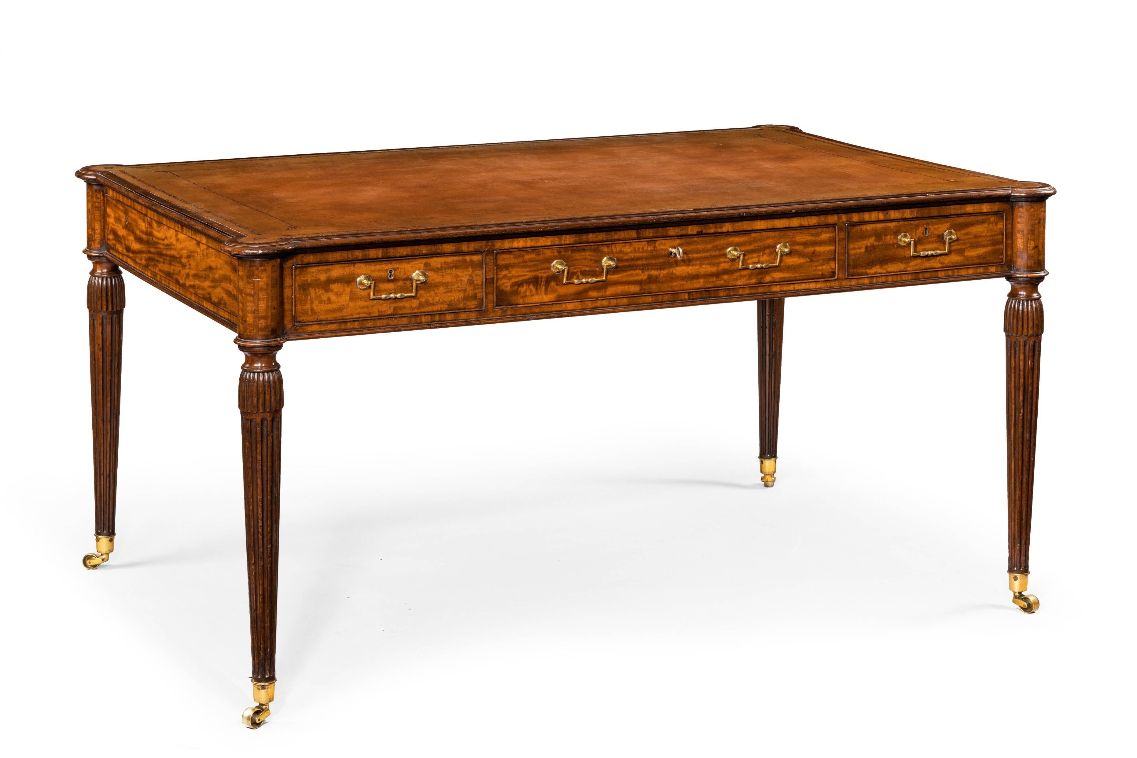 An elegant Sheraton period mahogany free standing writing table. Rectangular top with rounded projected corners. Turned tapering fluted legs topped with 'tassels'. Three mahogany lined frieze drawers with later brass handles. 
The whole is very much