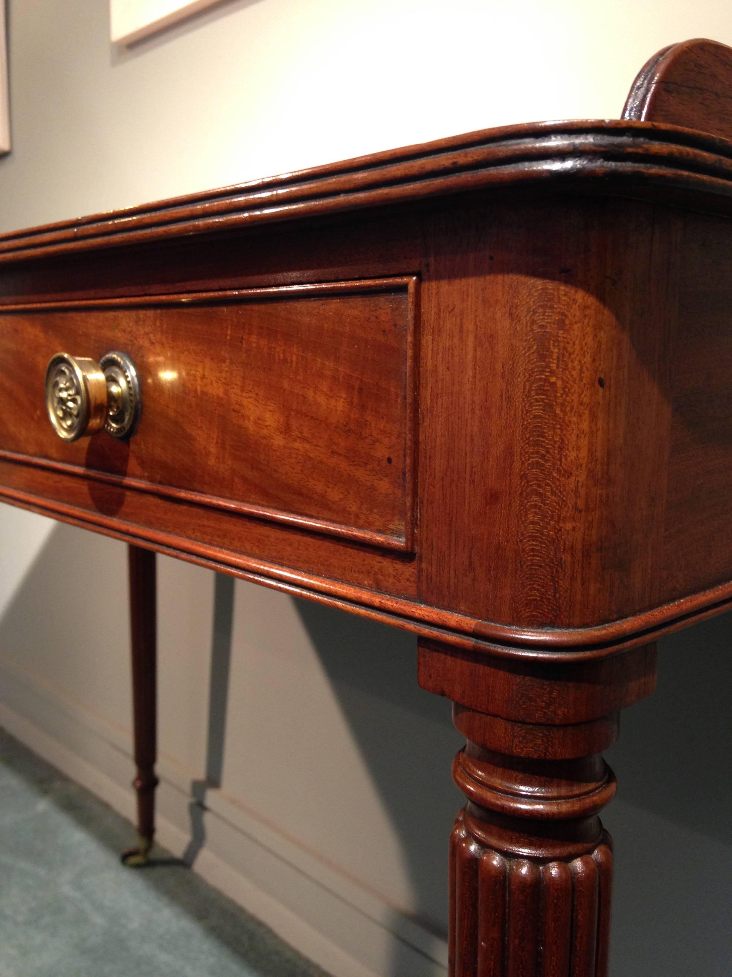 Regency mahogany dressing table by Gillows of Lancaster. The rectangular top has a reeded edge and a three-quarter solid gallery. The three cedar-lined frieze drawers have later brass knob handles. The whole has the Classic elegant long reeded