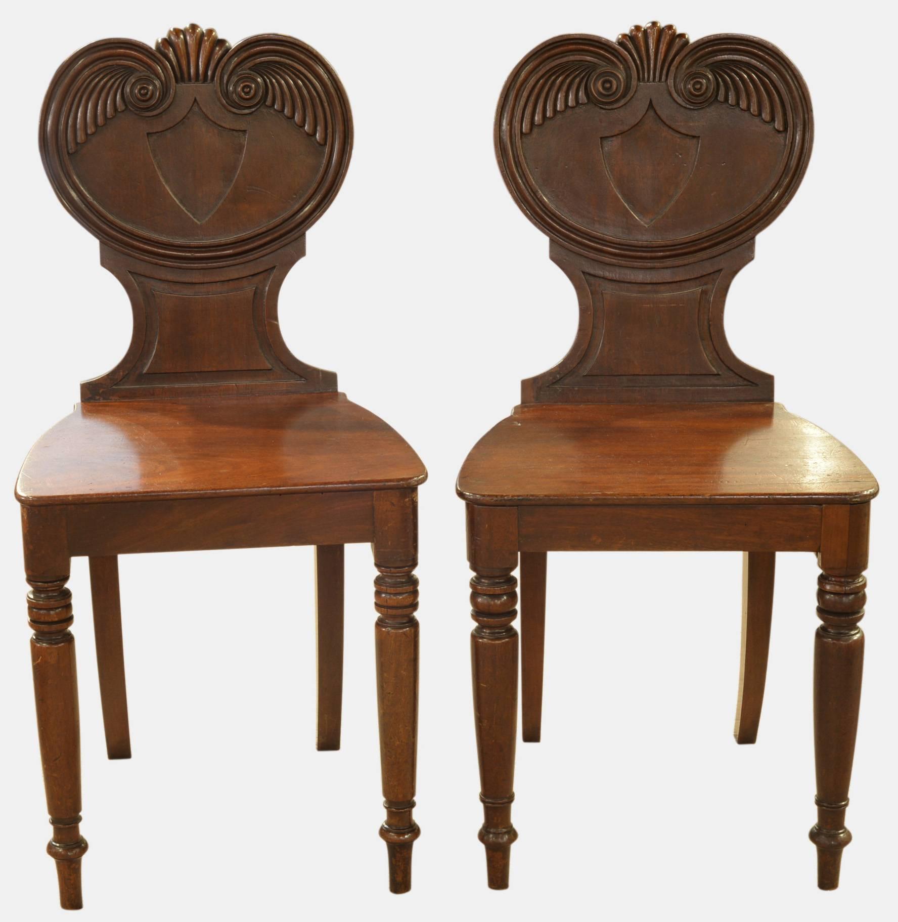 A pair of mahogany hall chairs on front turned legs, circa 1830.