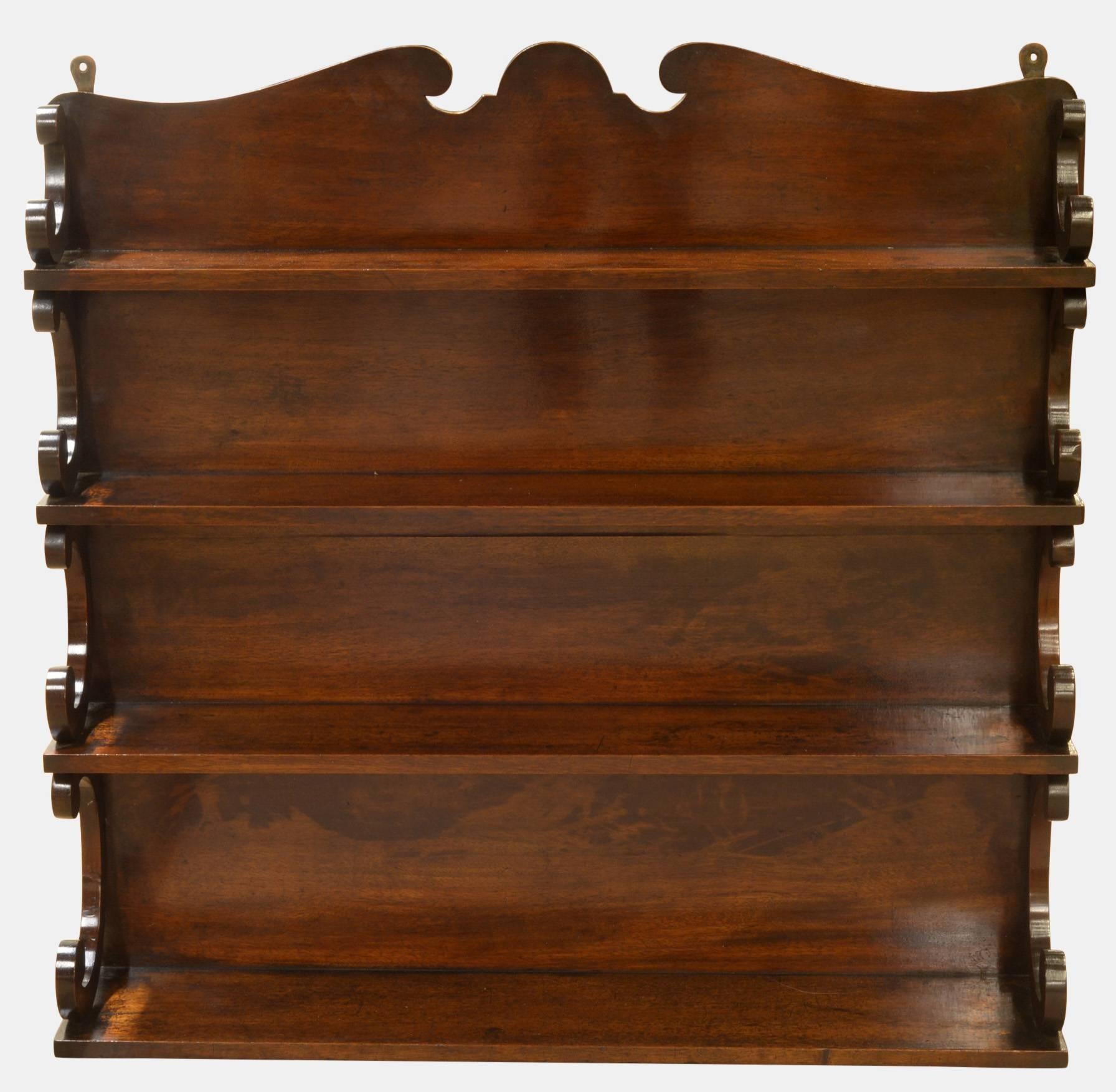 A set of mahogany hanging shelves with scrolled supports, 

circa 1820.