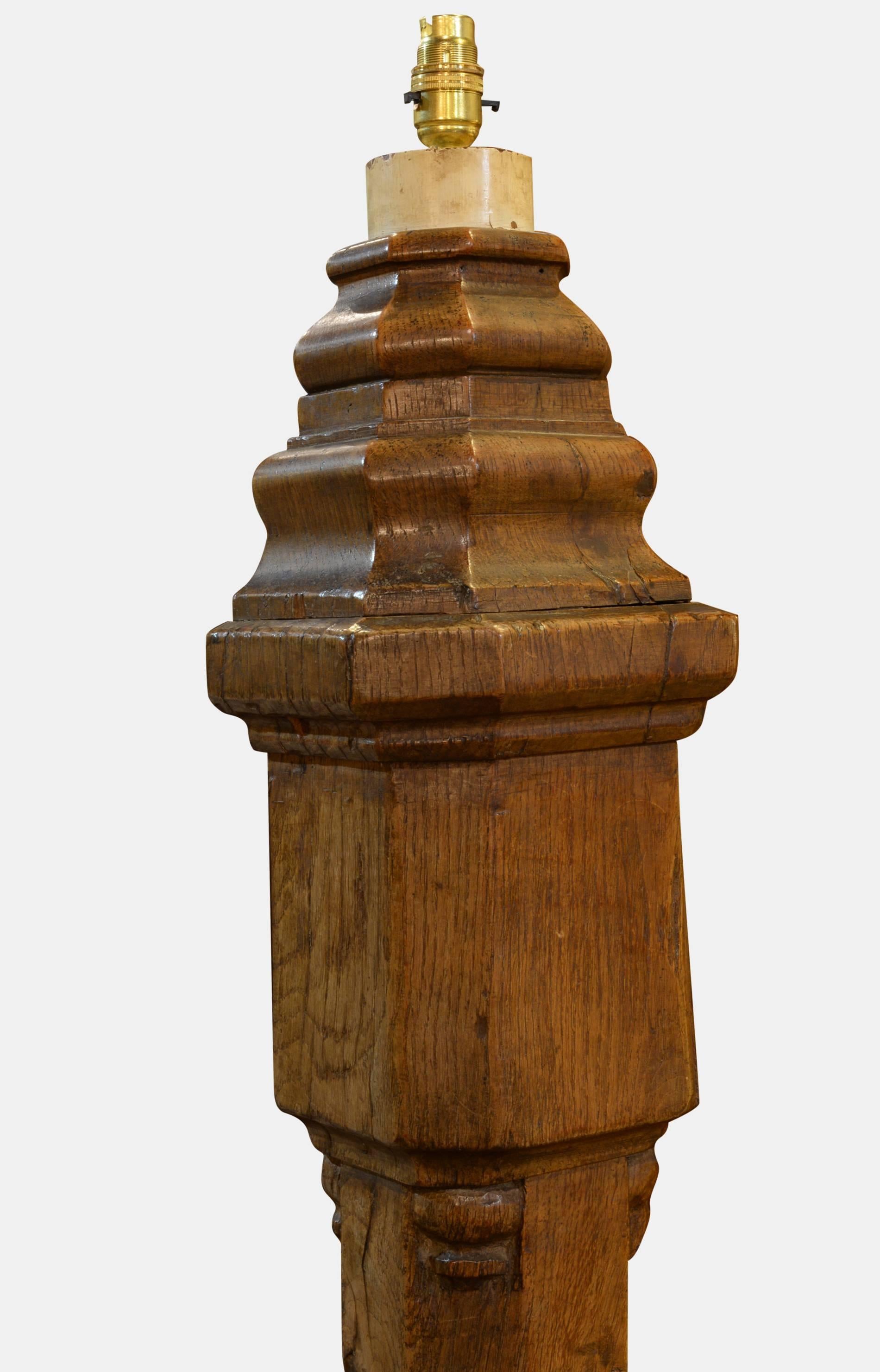 An impressive 16th-17th century oak newel post of fantastic color and patina. Later mounted as a lamp on sledge feet and moulded upper of late 19th-early 20th century.