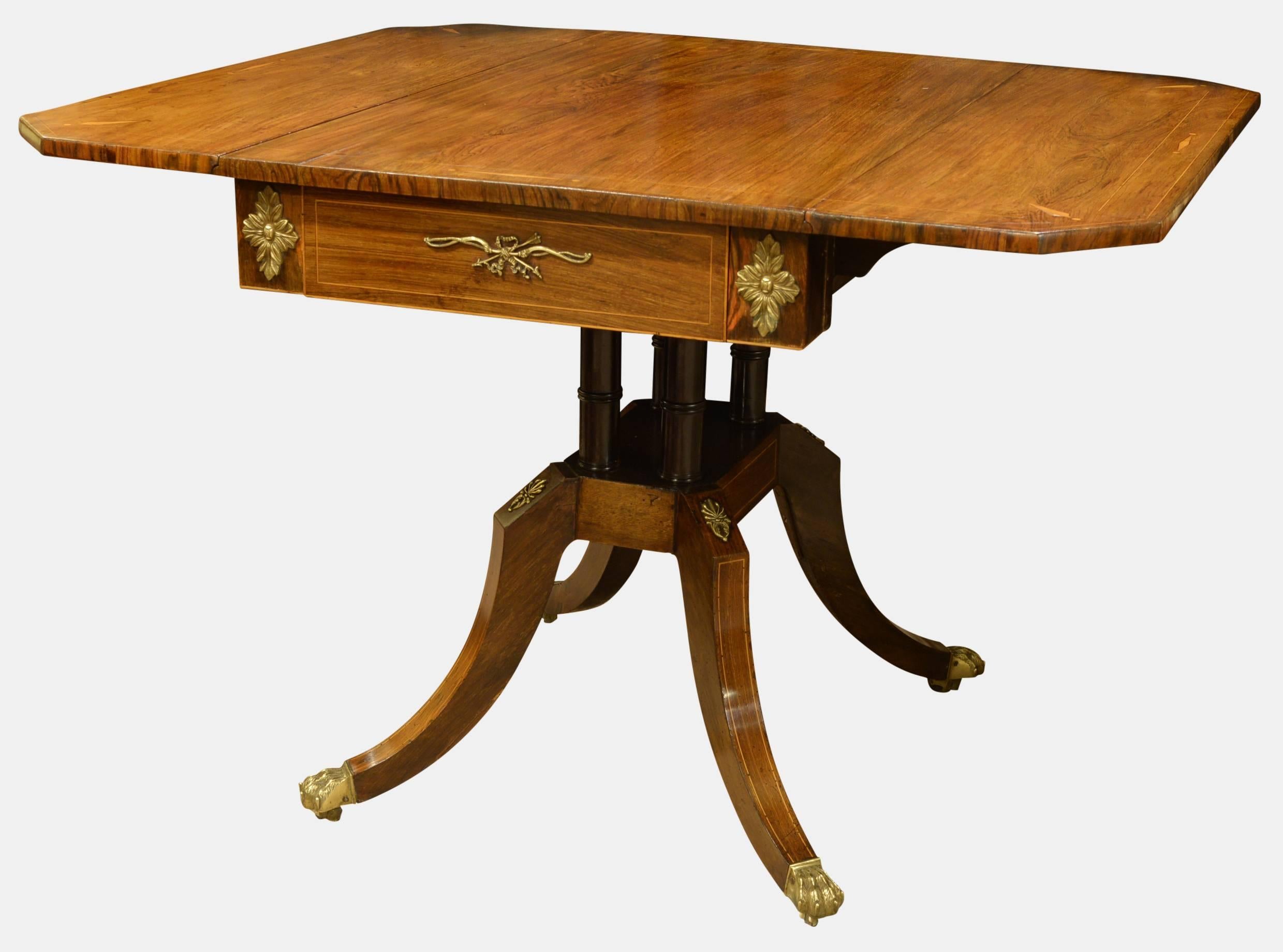A Regency rosewood drop-leaf supper table with stainwood banding and ormolu mounts on splayed legs,

circa 1820.