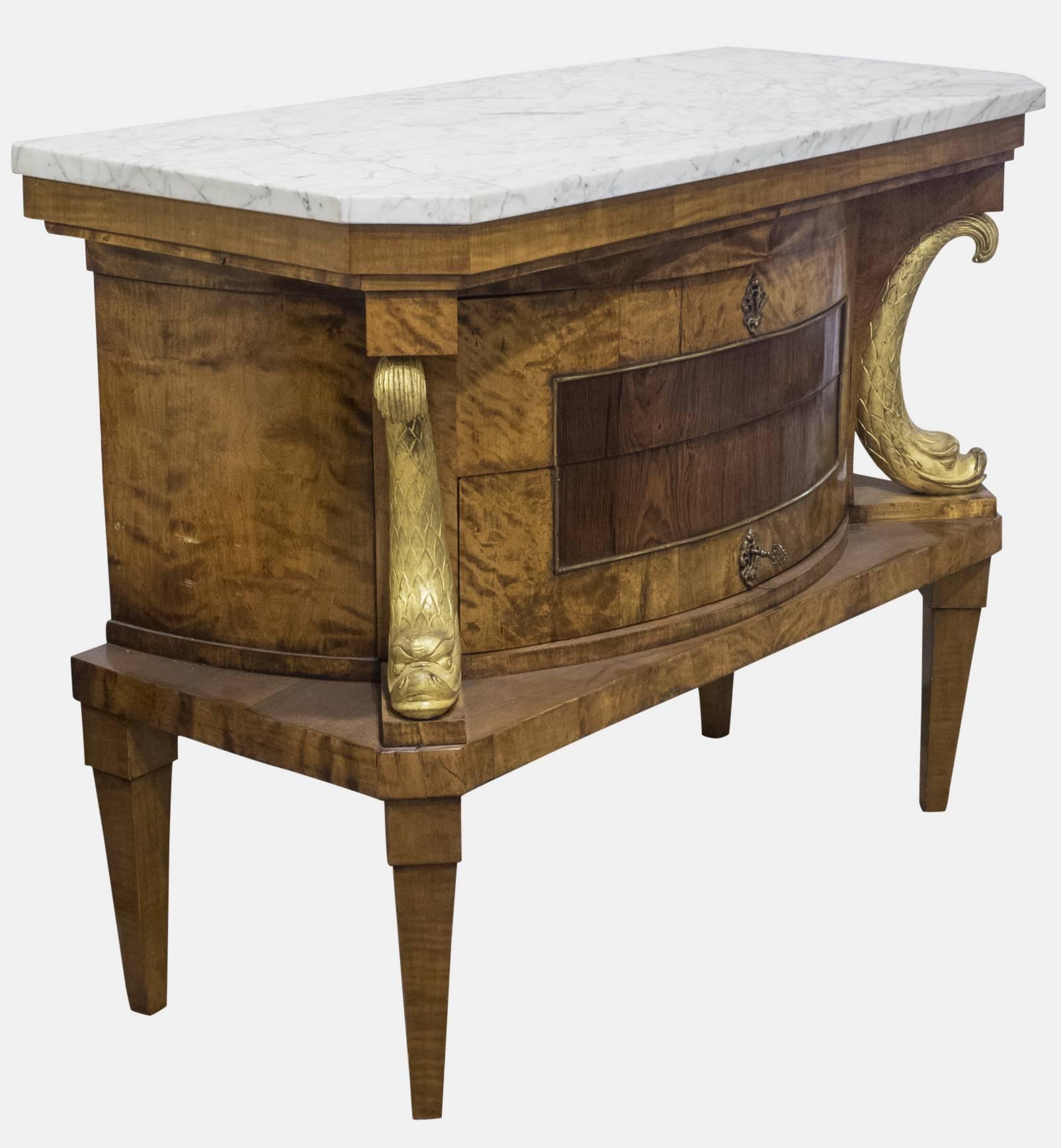 A Beidermeier style marble topped commode with gilded dolphin supports and bowed centre section with two drawers.