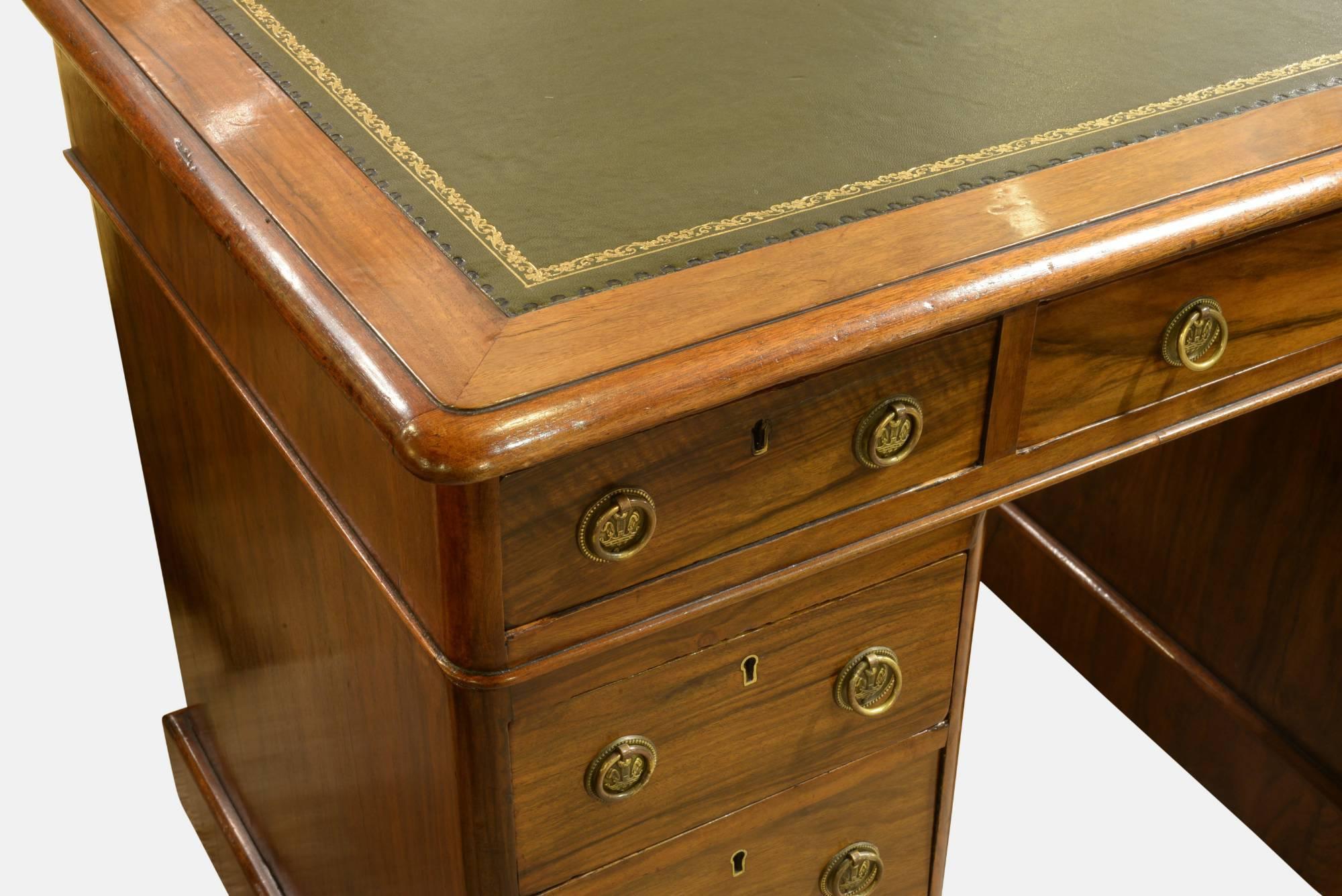 A Victorian walnut kneehole pedestal desk with green leather inset writing surface, circa 1880.