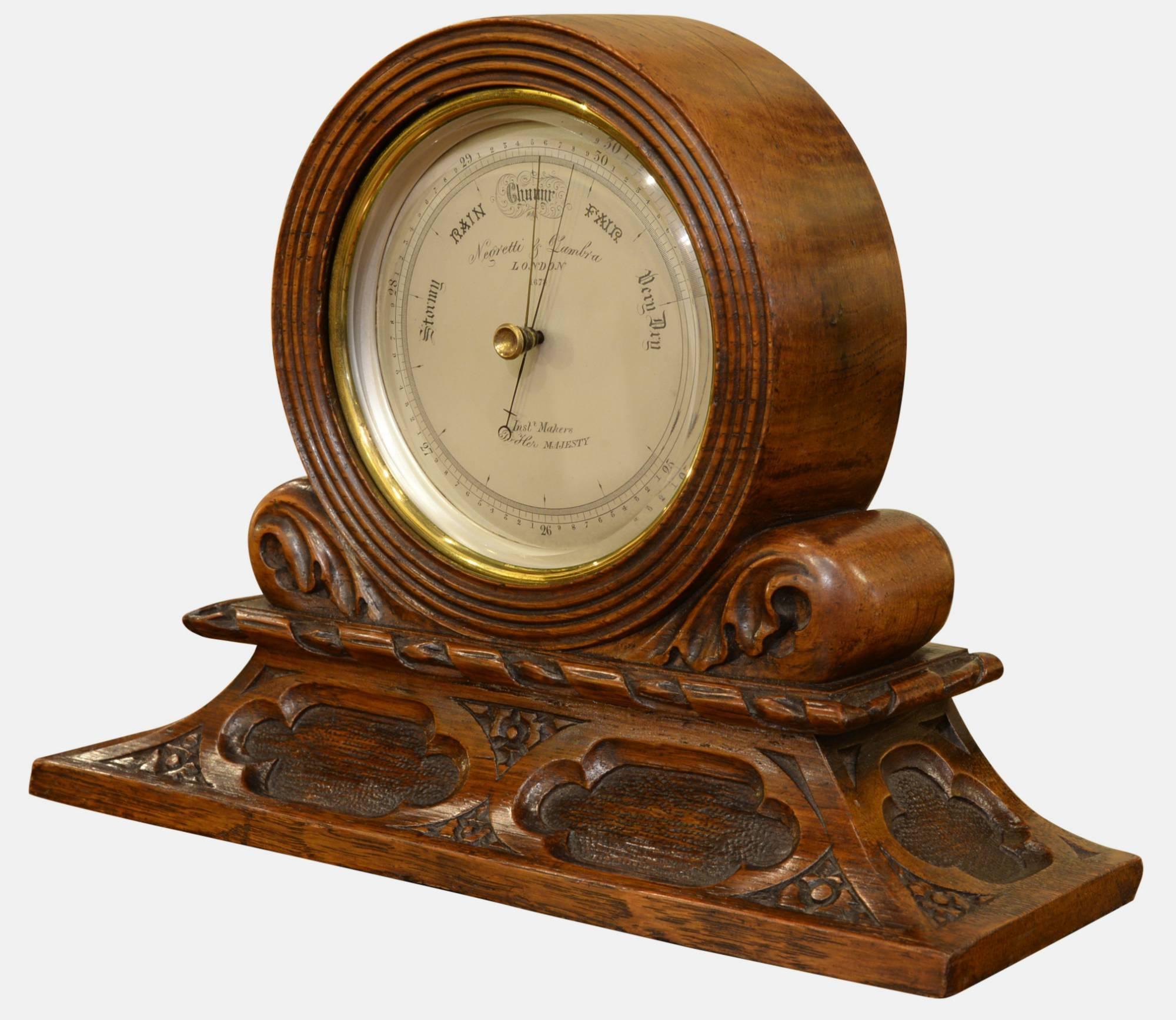 A Victorian brass desk aneroid barometer by Negretti & Zambra. In carved oak case.