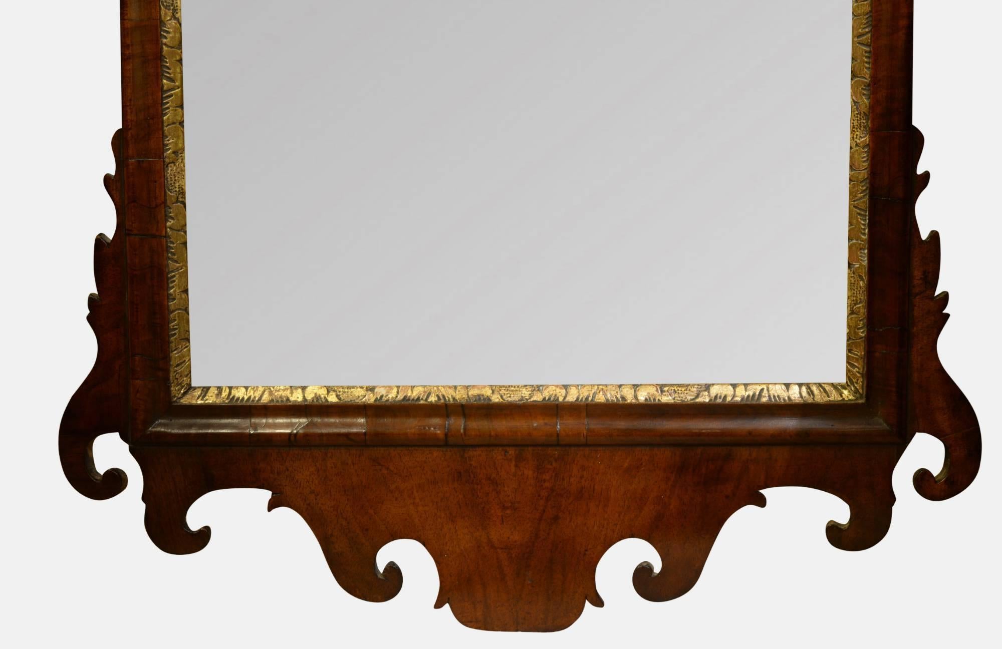George II walnut and parcel-gilt mirror with fretted and cross grain moulding. Pierced gilt leafy cartouche and original bevelled plate, 
circa 1740.
  