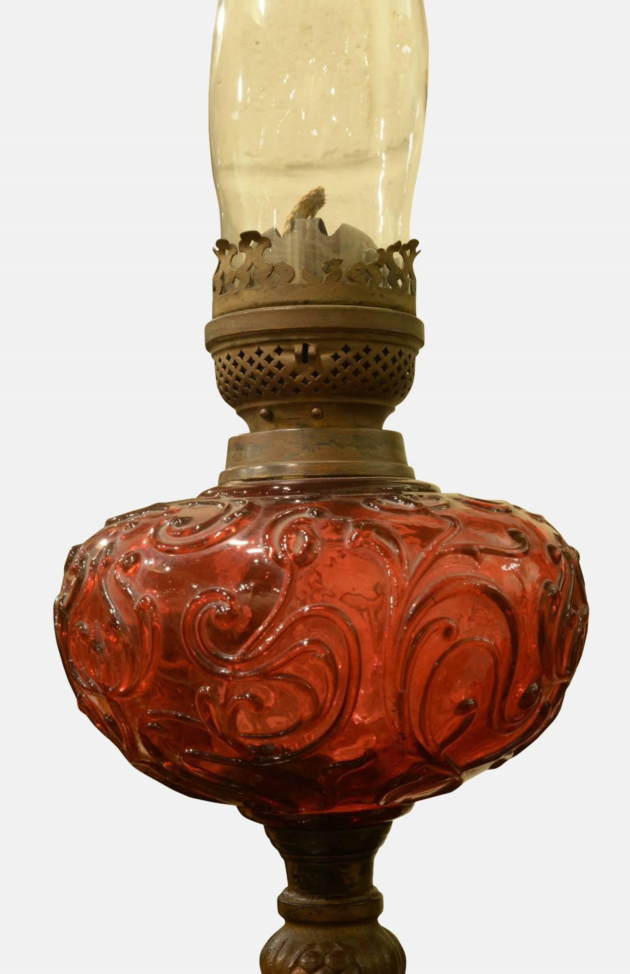 A late 19th century cranberry glass oil lamp.
 