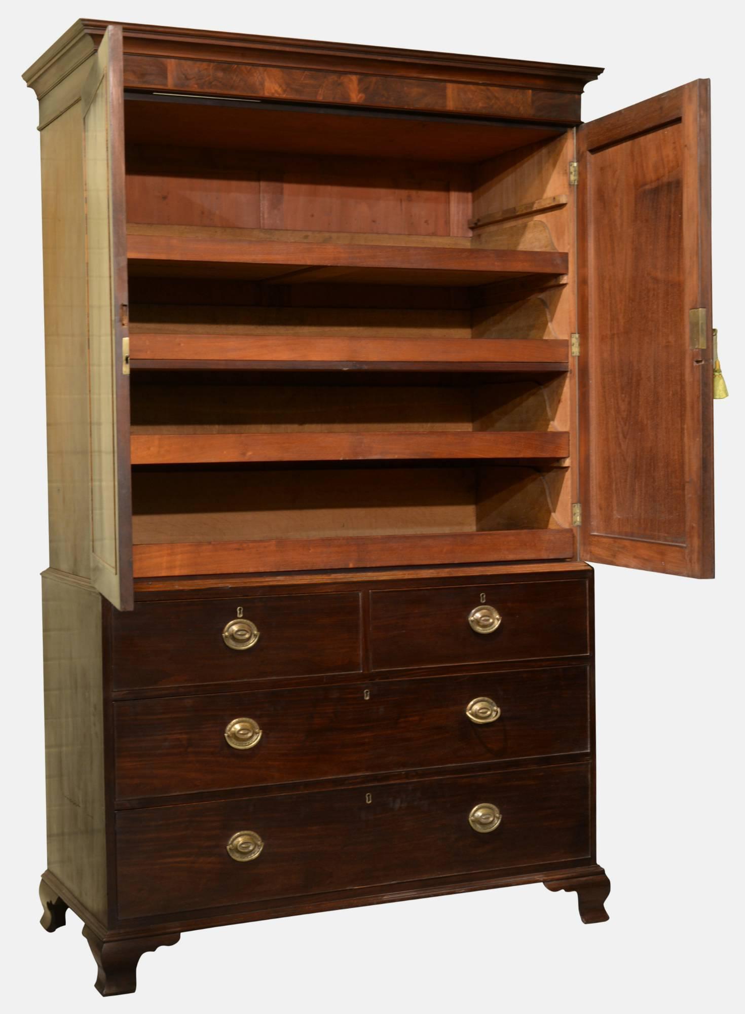 A George II linen press with flame mahogany door panels and decorative banding. The interior with four original slides, the base two short over two long drawers. Original over plate handles and ogee bracket feet, 

circa 1800.