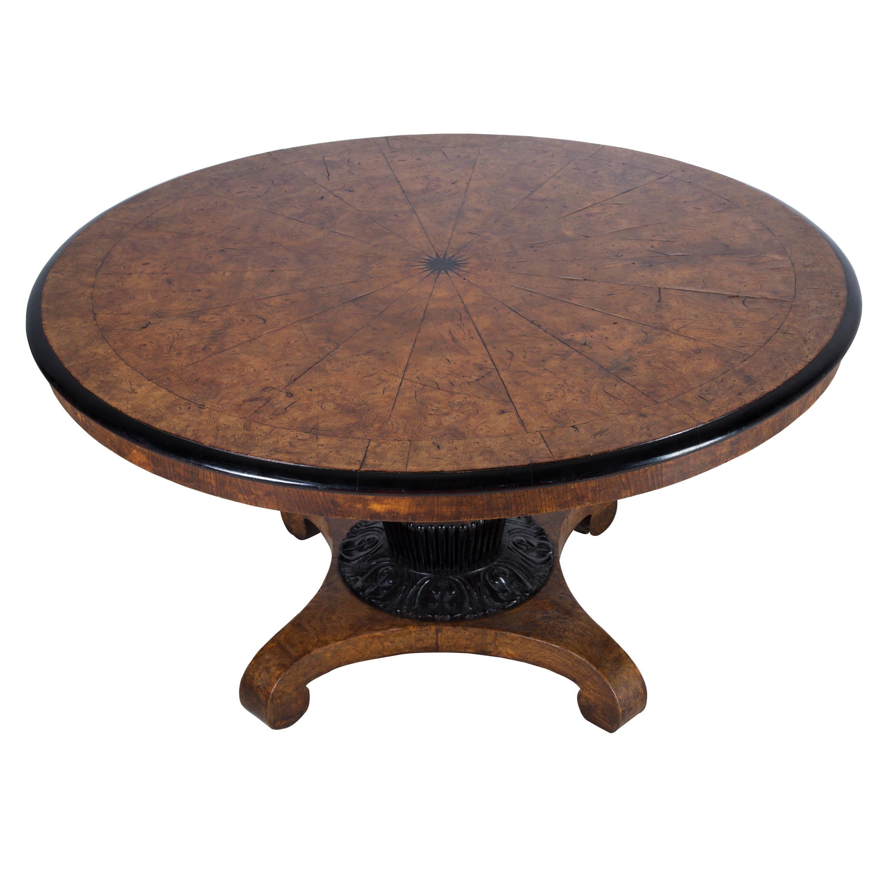 A 19th century burr elm and ebony centre table, the top centre inlaid with an 18 point ebony star surrounded by 18 segments of matching burr elm and then banded in burr elm, the whole top surrounded by an ebonized moulding, the top standing on an