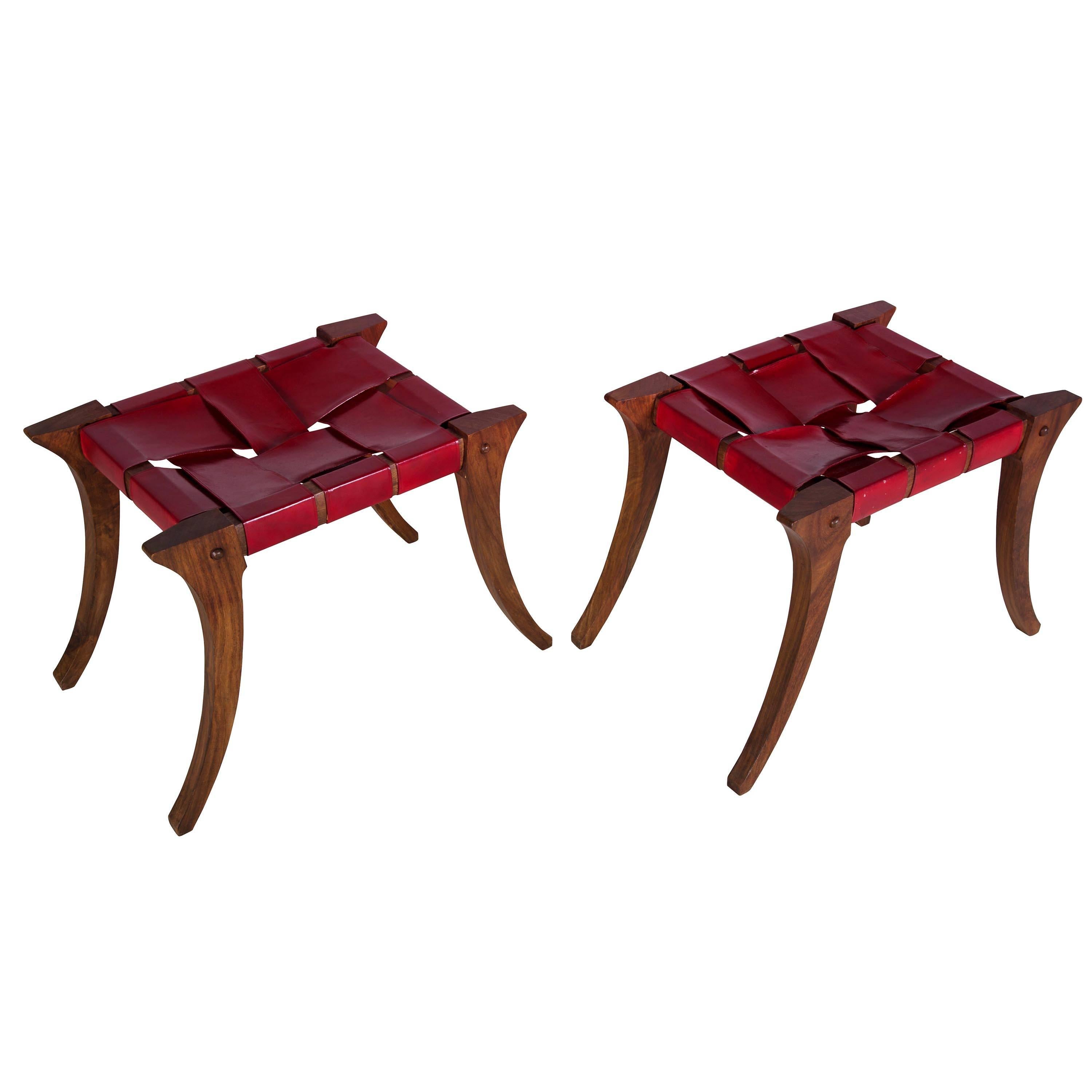Pair of Klismos stools in the manner of T. H. Robsjohn-Gibbings, circa 1950s. Worn leather seats which have been stained red at a later date.