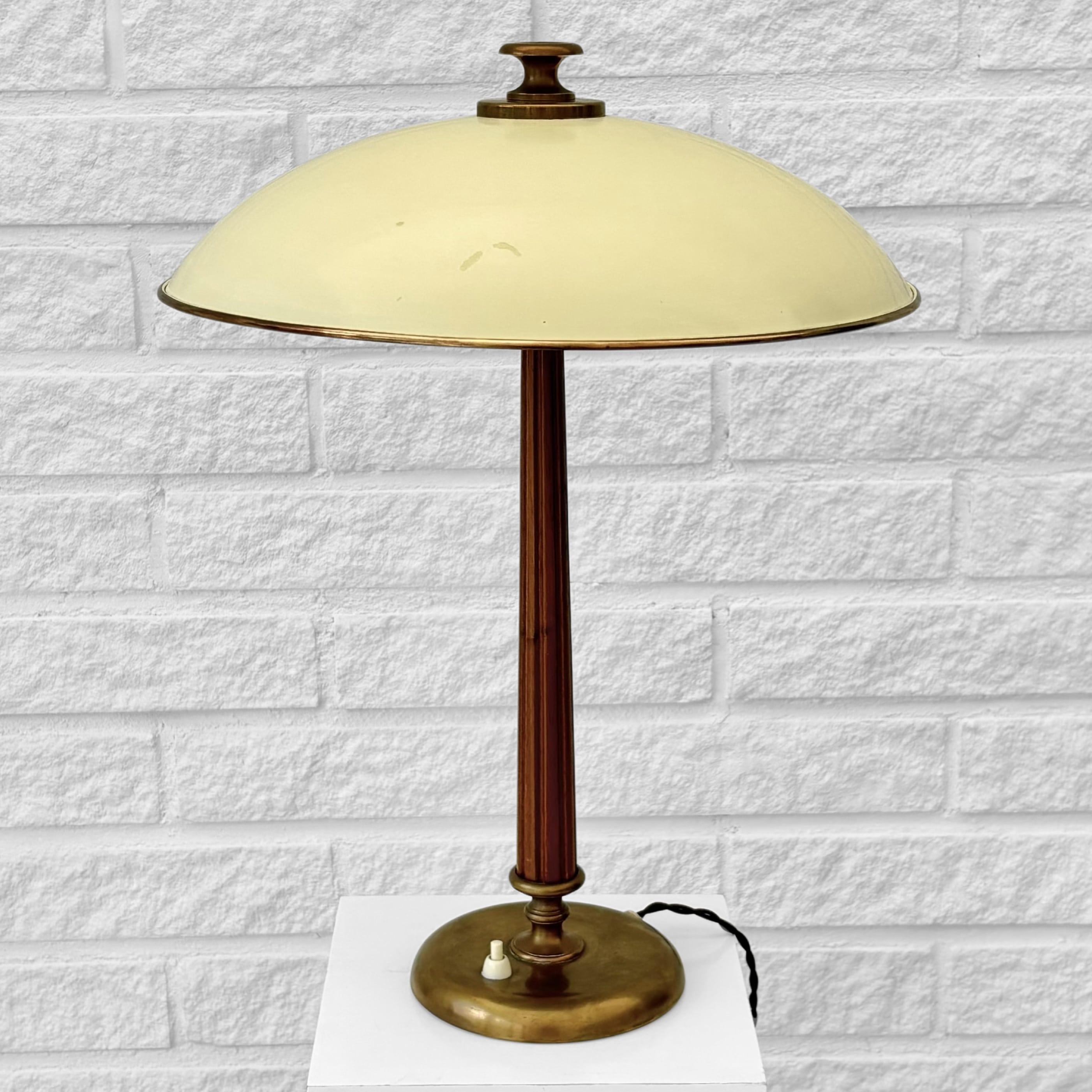 A Scandinavian modern table lamp, model 15625, produced by Swedish manufacturer Arvid Böhlmarks Lampfabrik in the 1930s. Expertly crafted, the lamp features a polished oak stem with intricate relief detailing, resting on a round brass base with an