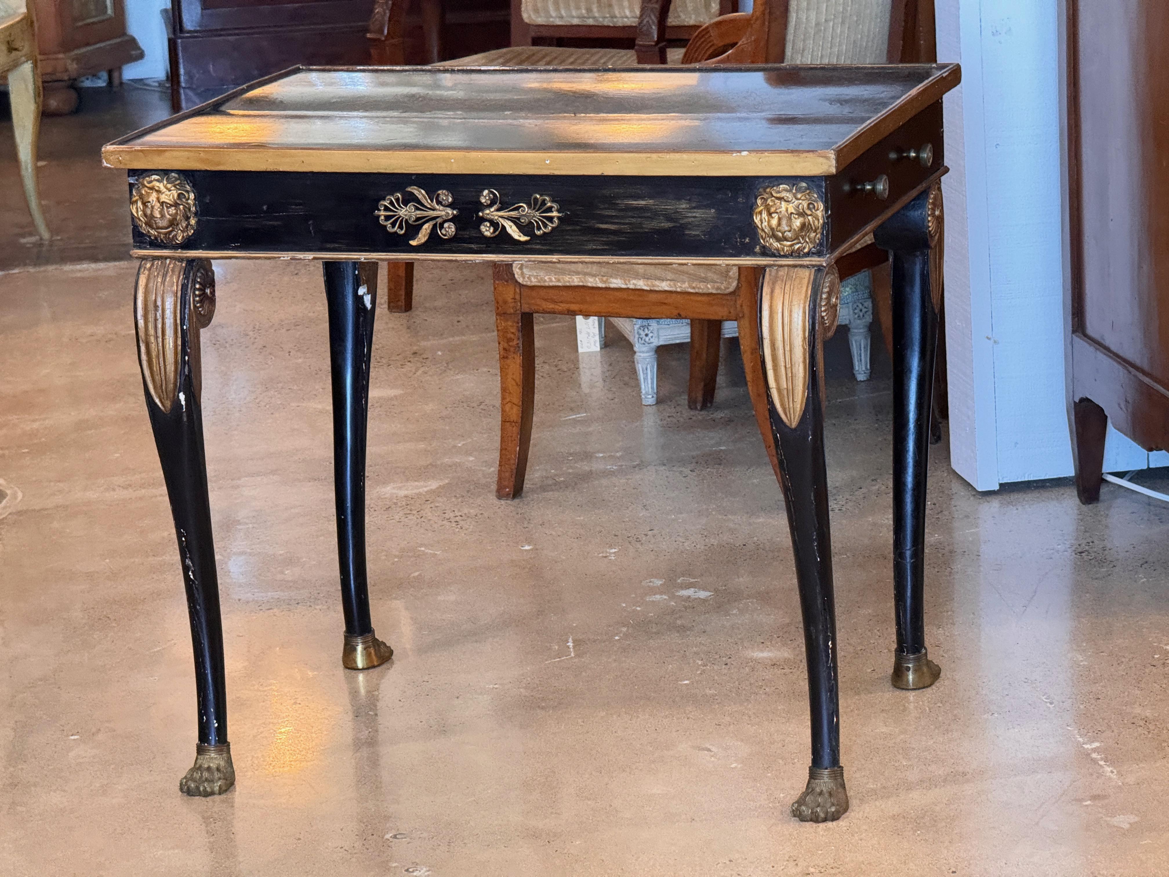 Table d'appoint d'époque Napoléon III avec finition ébonisée et détails dorés. Les caractéristiques comprennent un tiroir unique, des montures de masque de lion à chaque coin, des pieds fuselés avec des pattes, et des appliques de feuillage