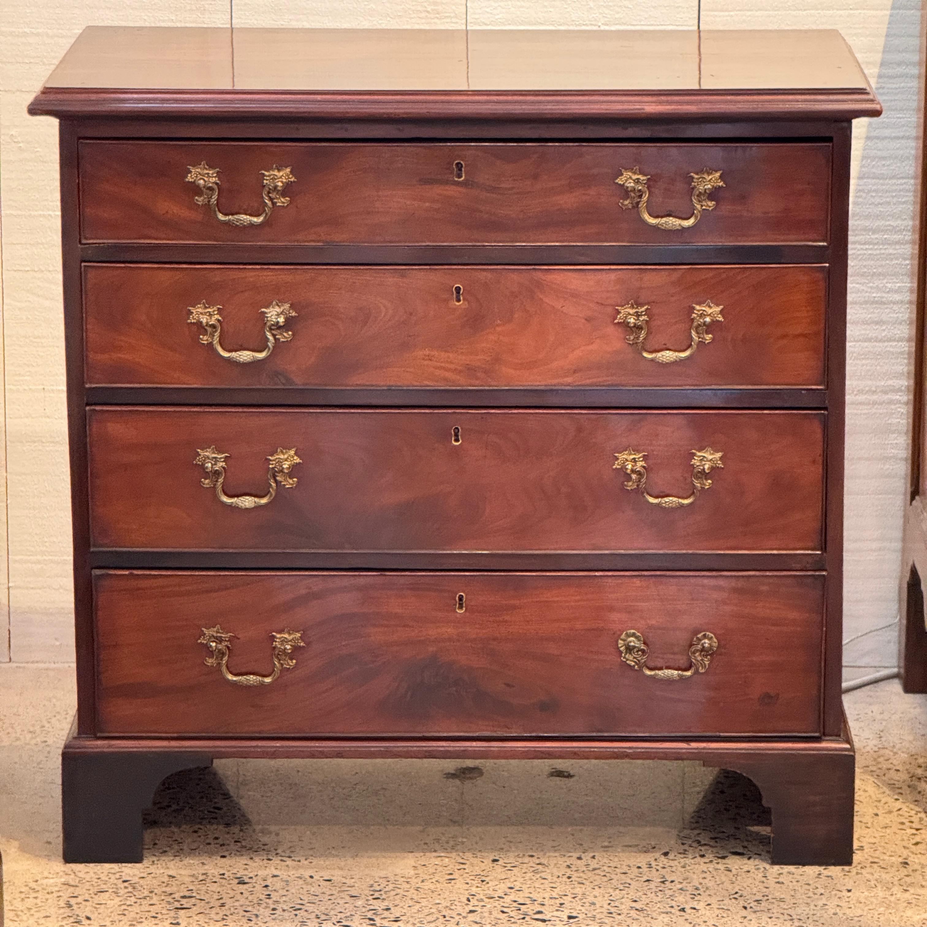 Late 18th century mahogany chest with four graduated drawers, featuring original brass pulls and bracket feet. The top edge is molded, and the drawer construction shows fine dovetail joinery. A simple, classic English form with rich grain and warm