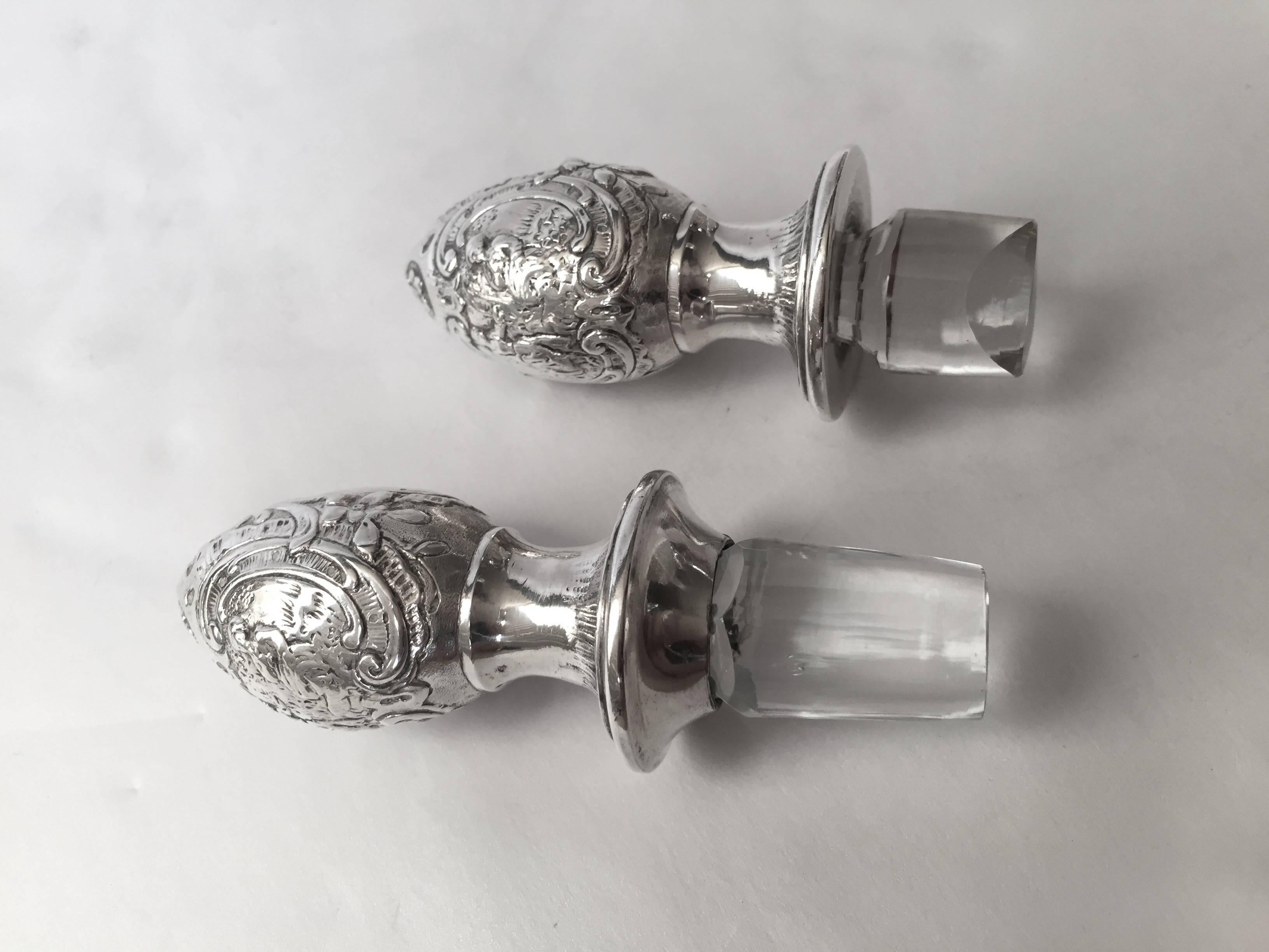 A large pair of rare and unusual shaped decanters of English sterling and etched glass. Fantastic subject matter in the pierced silver decoration the etched glass expertly rendered the stoppers also please. In excellent condition ready to serve on