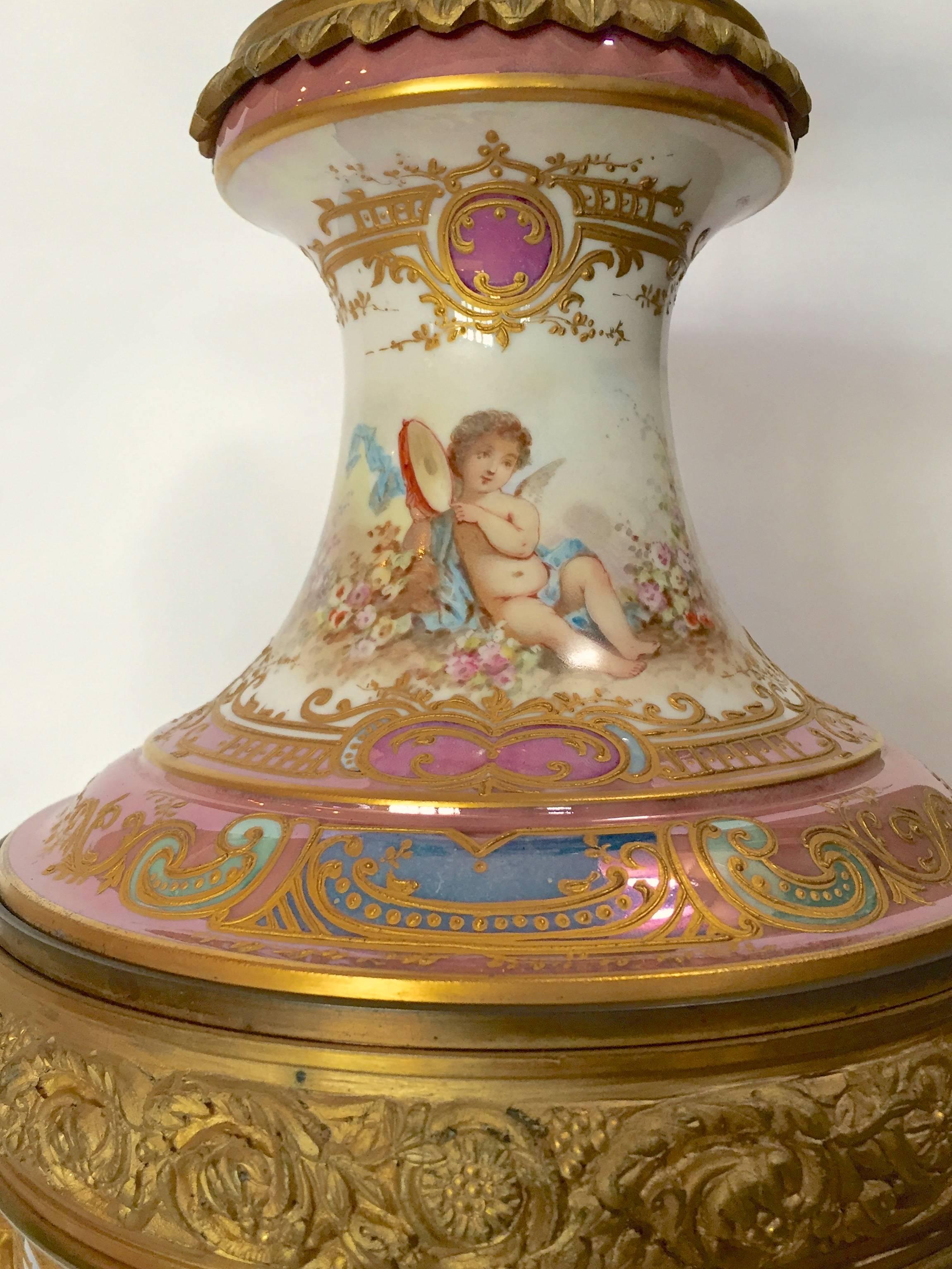 Wow! is this urn now converted to a lamp over the top beautiful, hand-painted scene of a beauty and cupid, love is in the air. The expert artistry highlighted by gorgeous raised paste gilt so precise and tight the multi colored enamels with